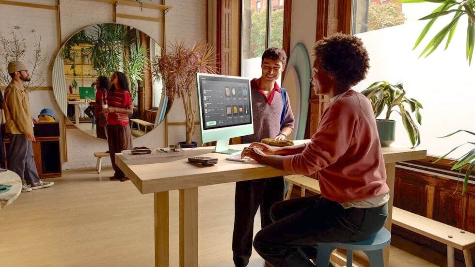 A woman seated at a table using a Mac desktop