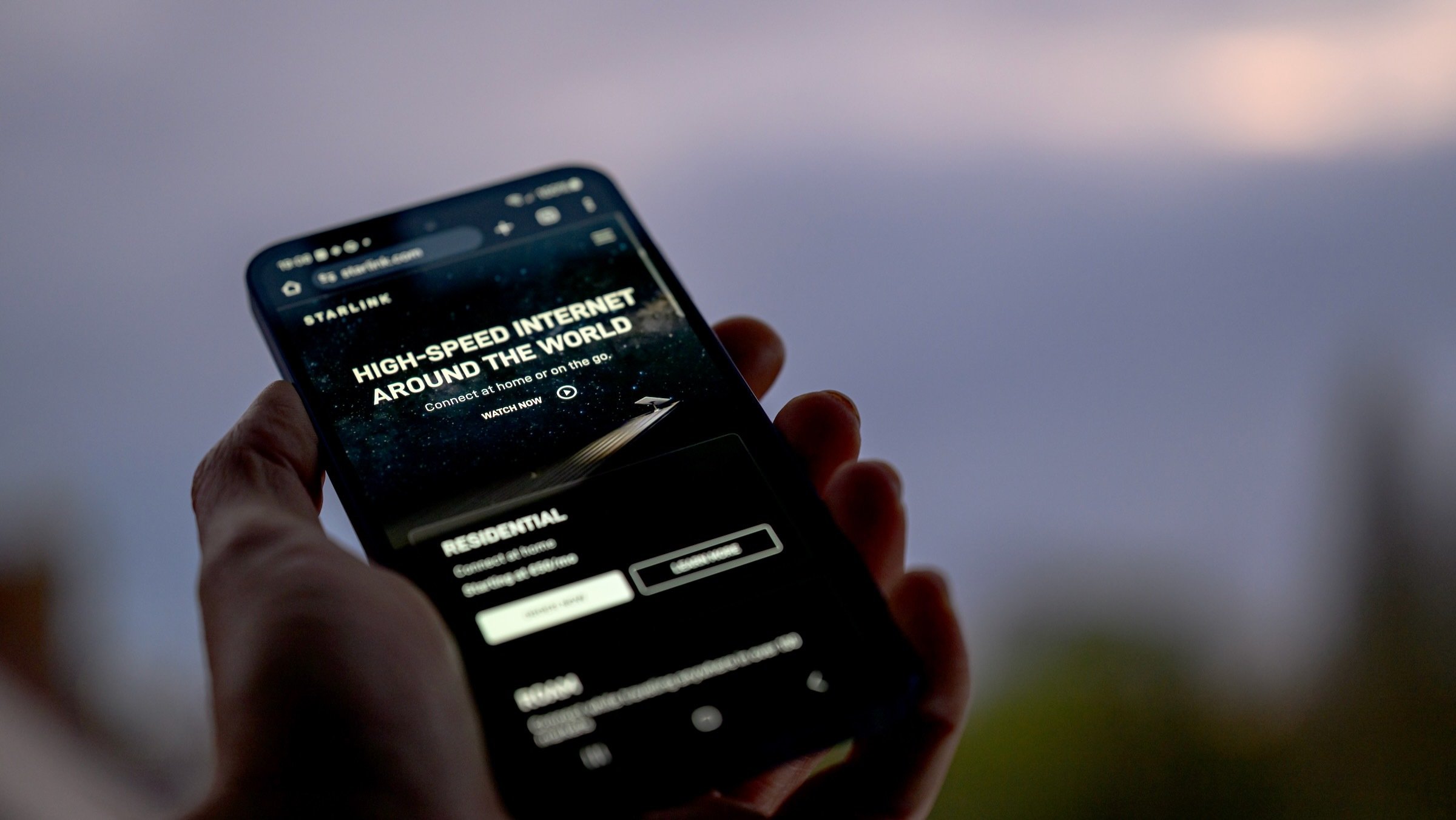 Starlink webpage displays on a mobile phone held in a hand outdoors