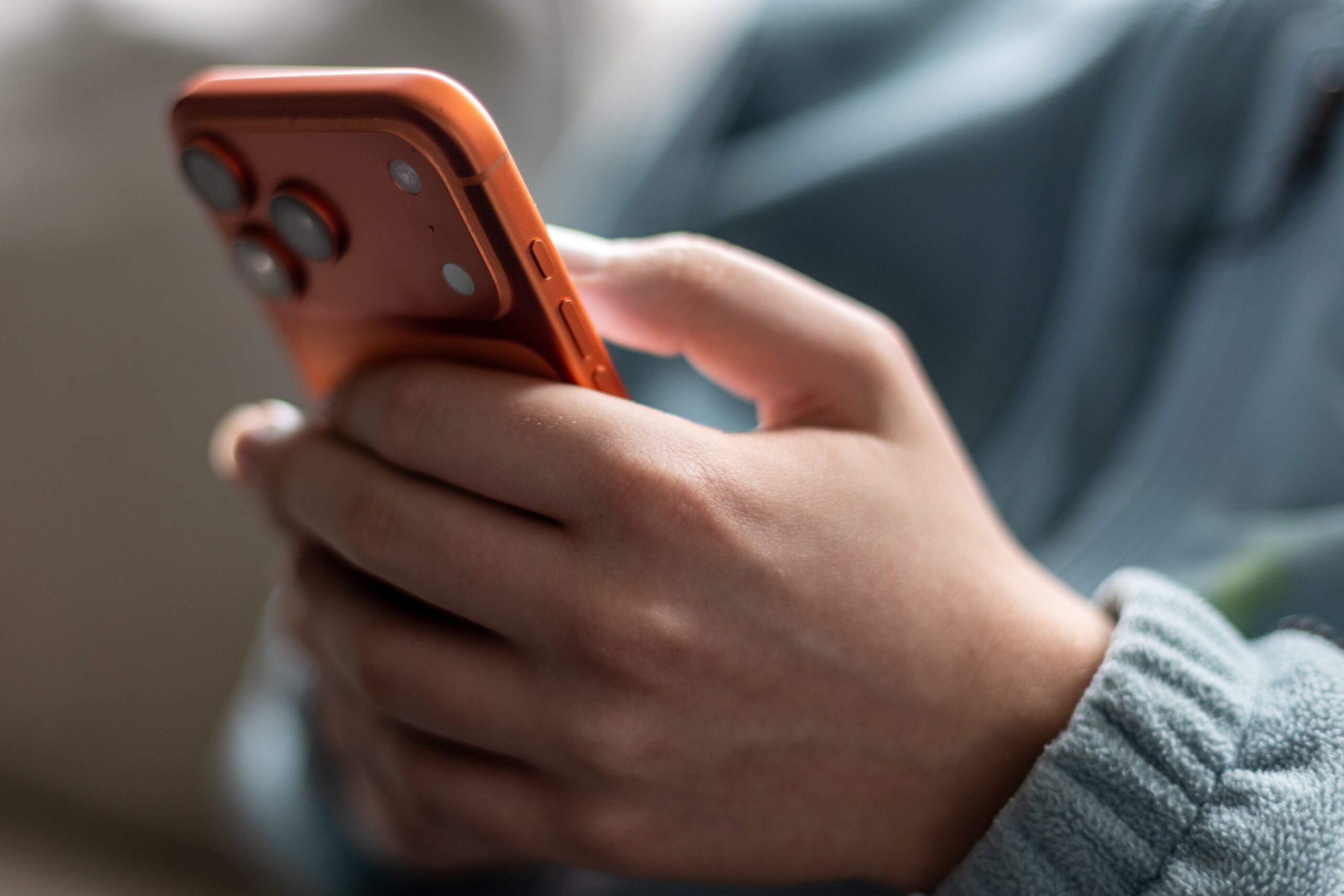 A close up photo of a child's hand holding an iPhone.