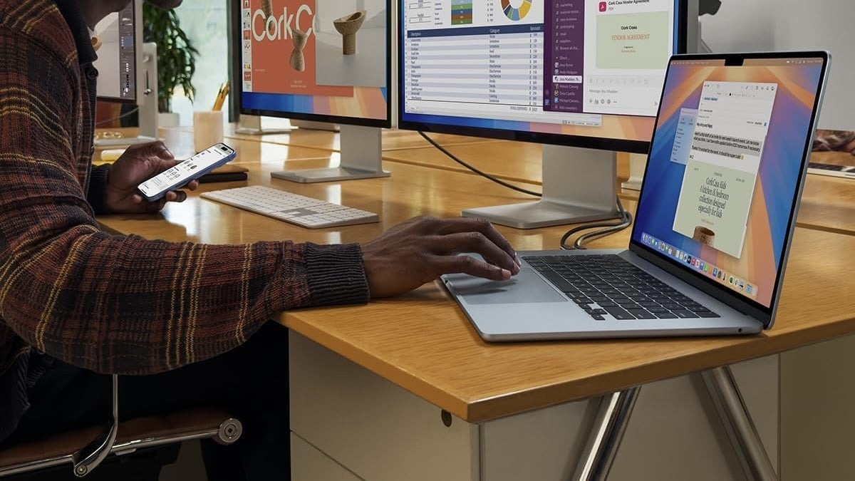 person sitting at desk working on macbook air connected to two external displays