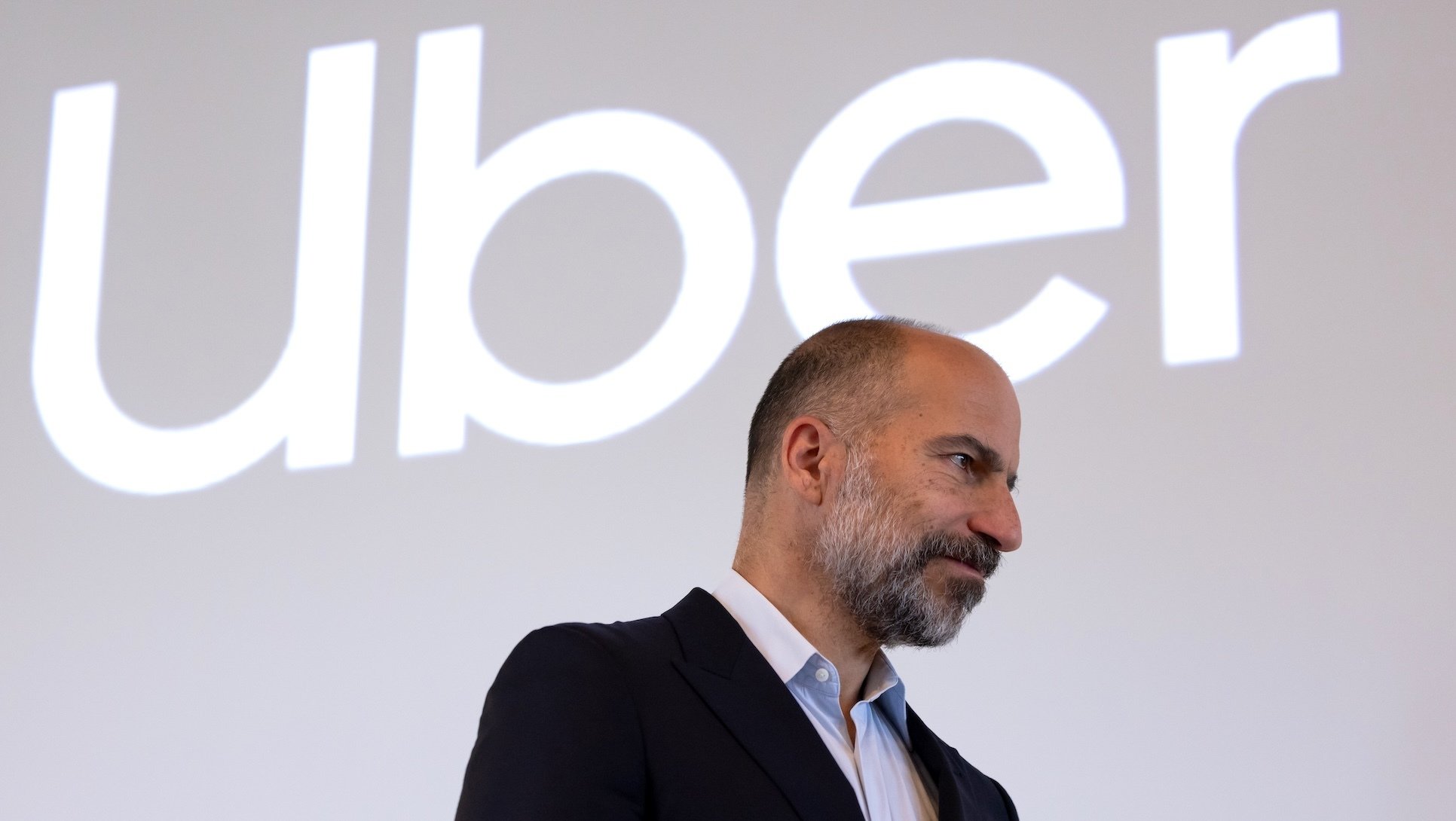 The Uber logo above its CEO, who is looking pensive