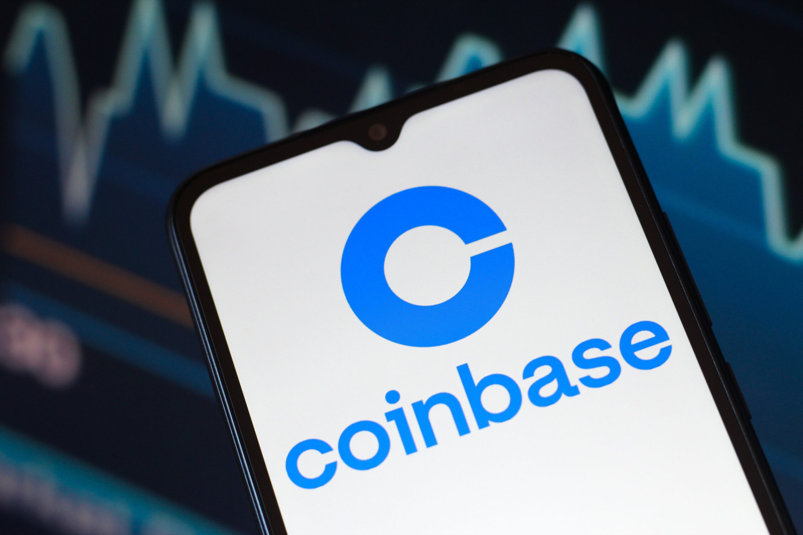 The Coinbase logo is seen displayed on a smartphone screen.