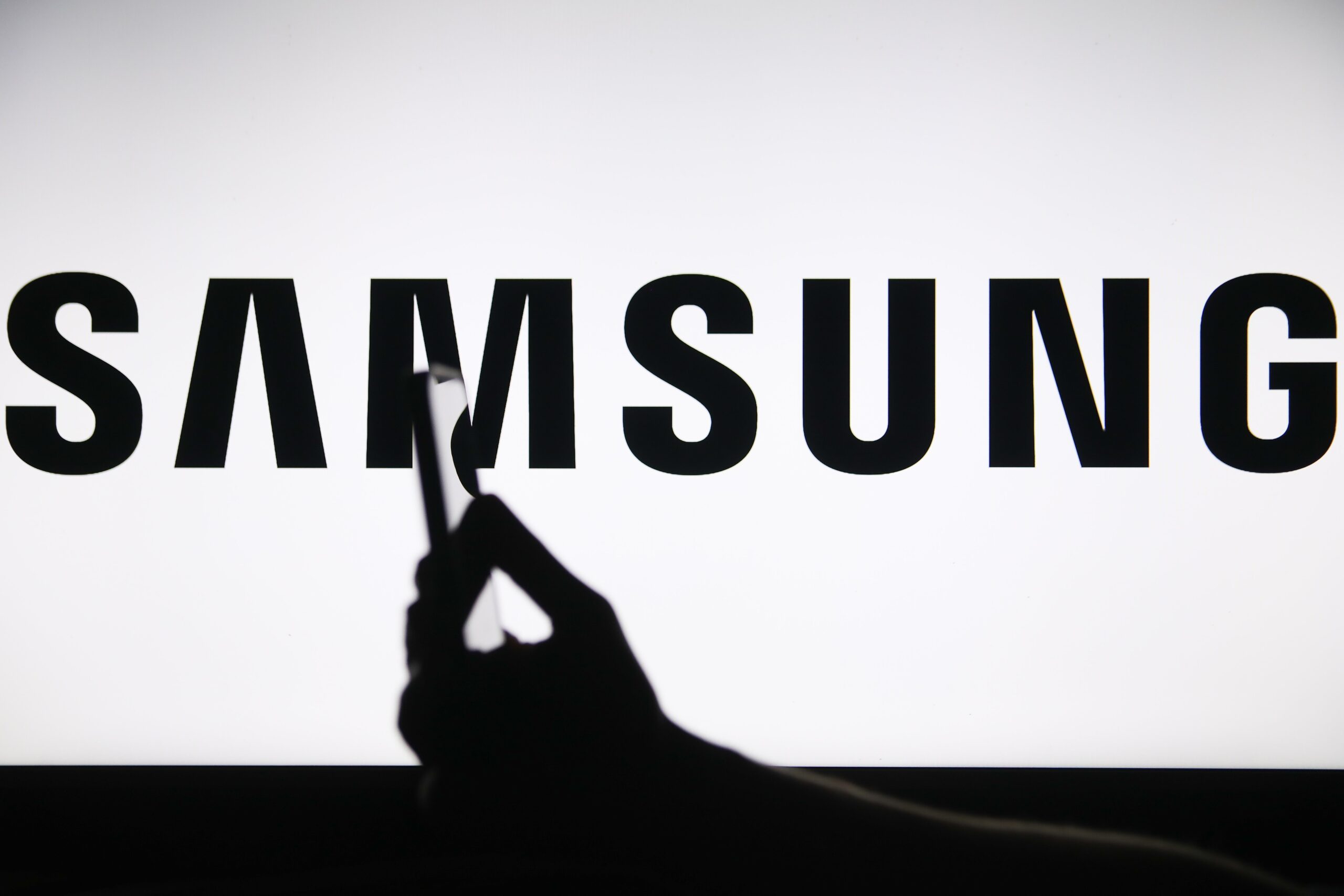 The Samsung logo displays on a screen with a person holding a phone