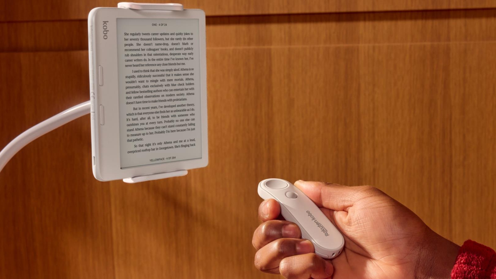 A person holding a Kobo remote while reading a Kobo Libra Colour