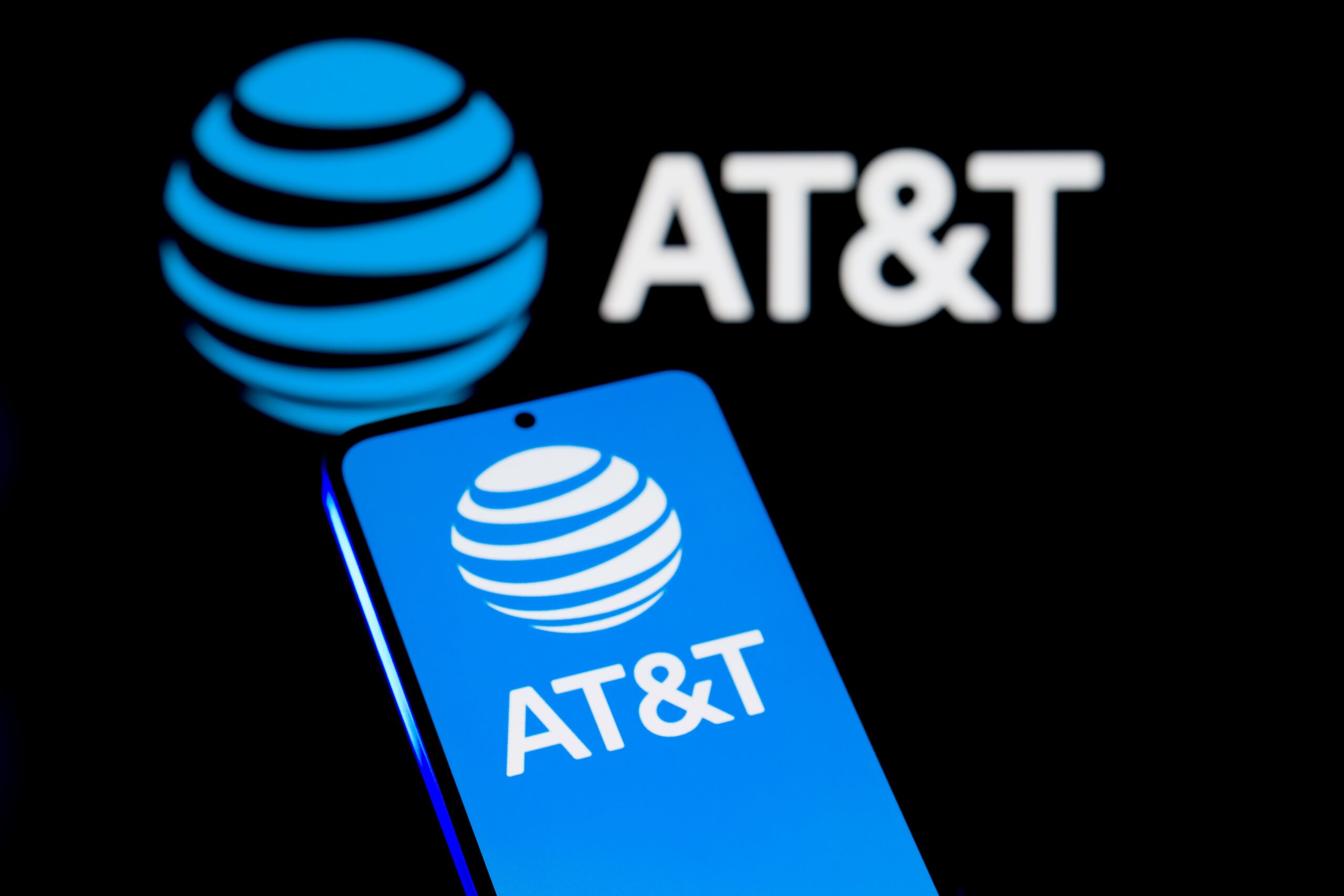 A phone displays the blue AT&T logo in front of a dark background.