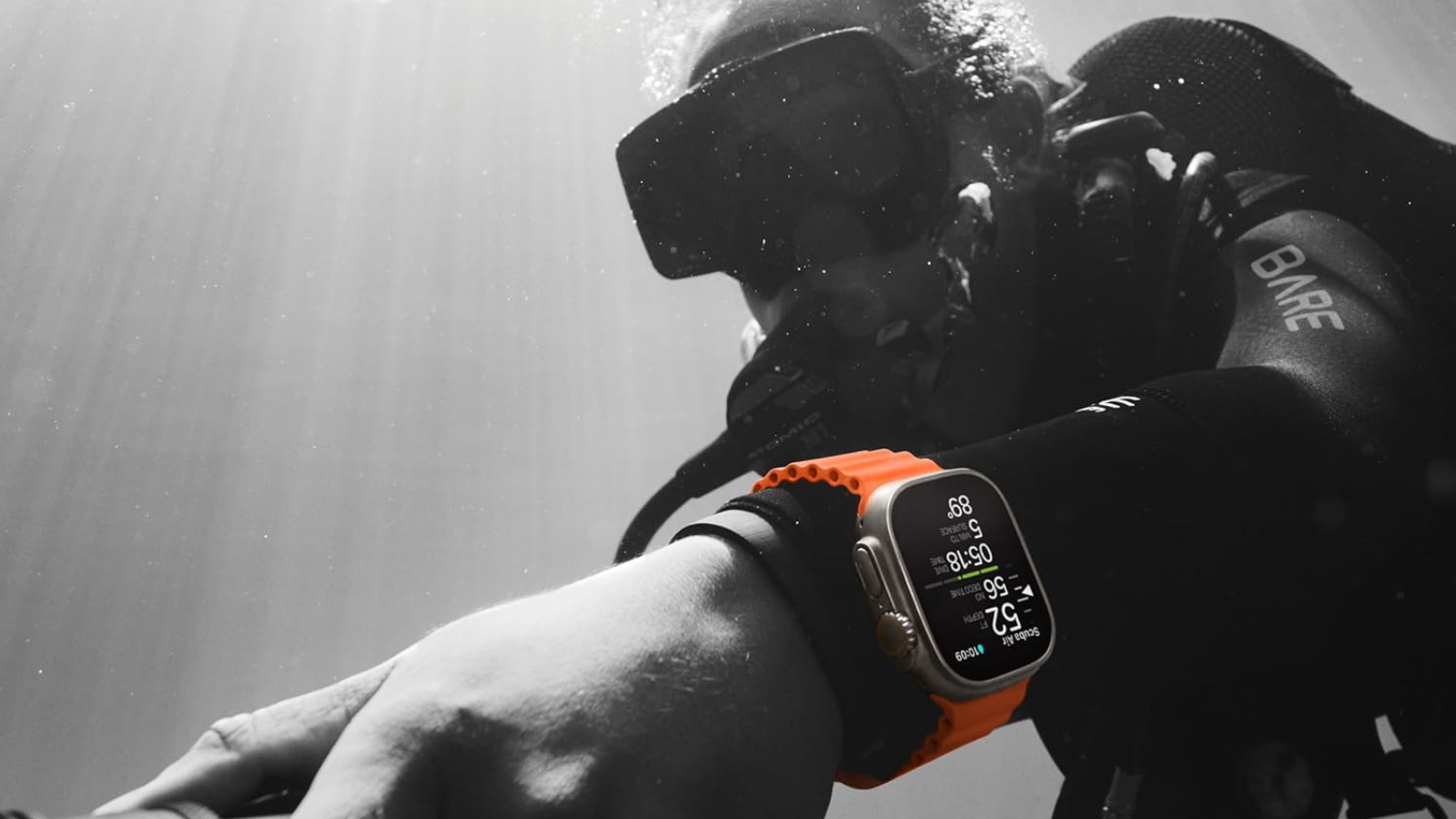 man underwater in black and white wearing orange Apple Watch Ultra 2