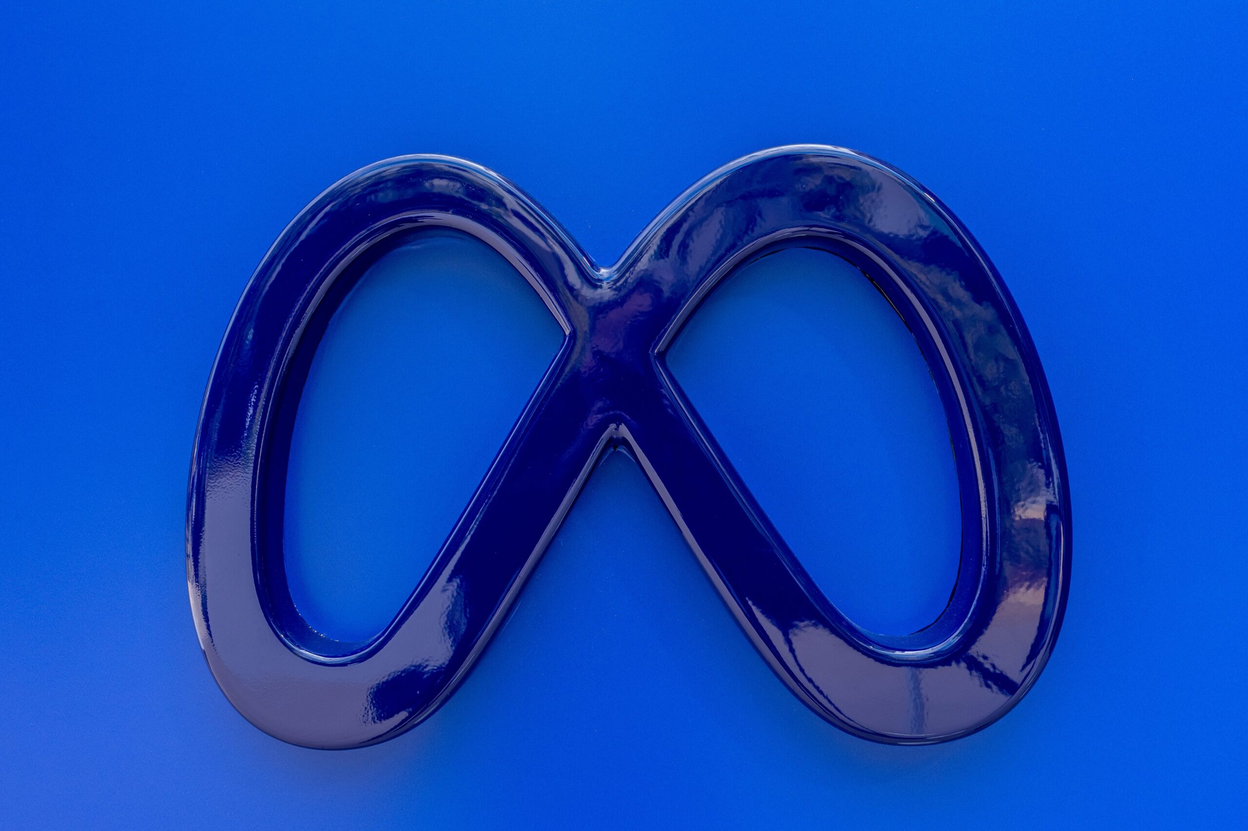 A Meta logo sign on a blue wall.