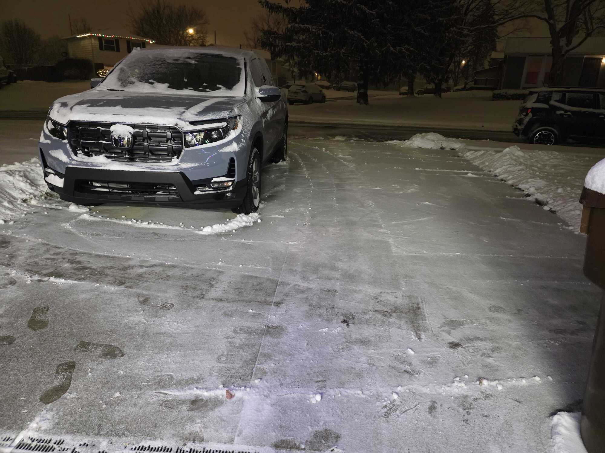 photo of a snow-covered car in icy driveway at night