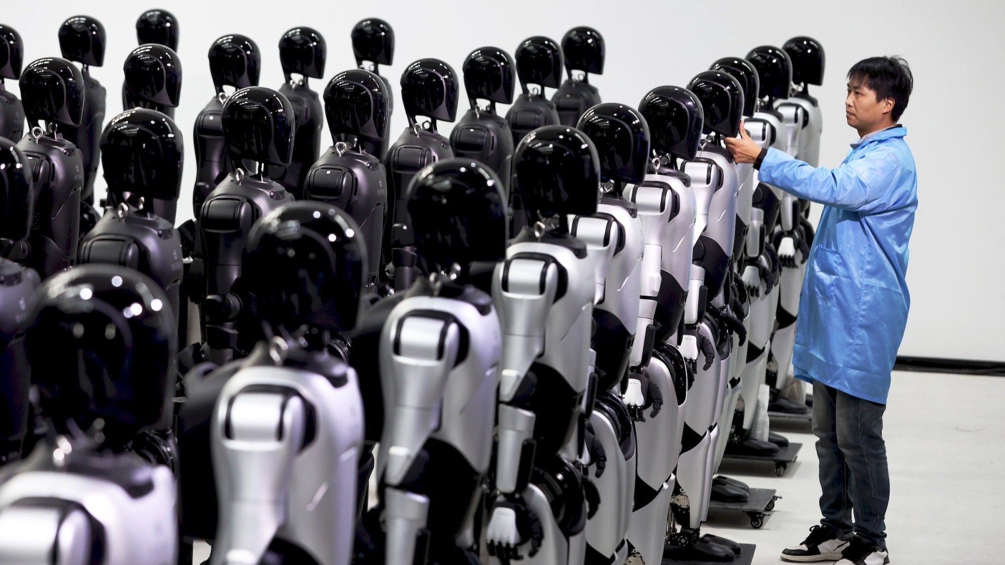 chinese engineer examining fleet of humanoid robots in AgiBot factory