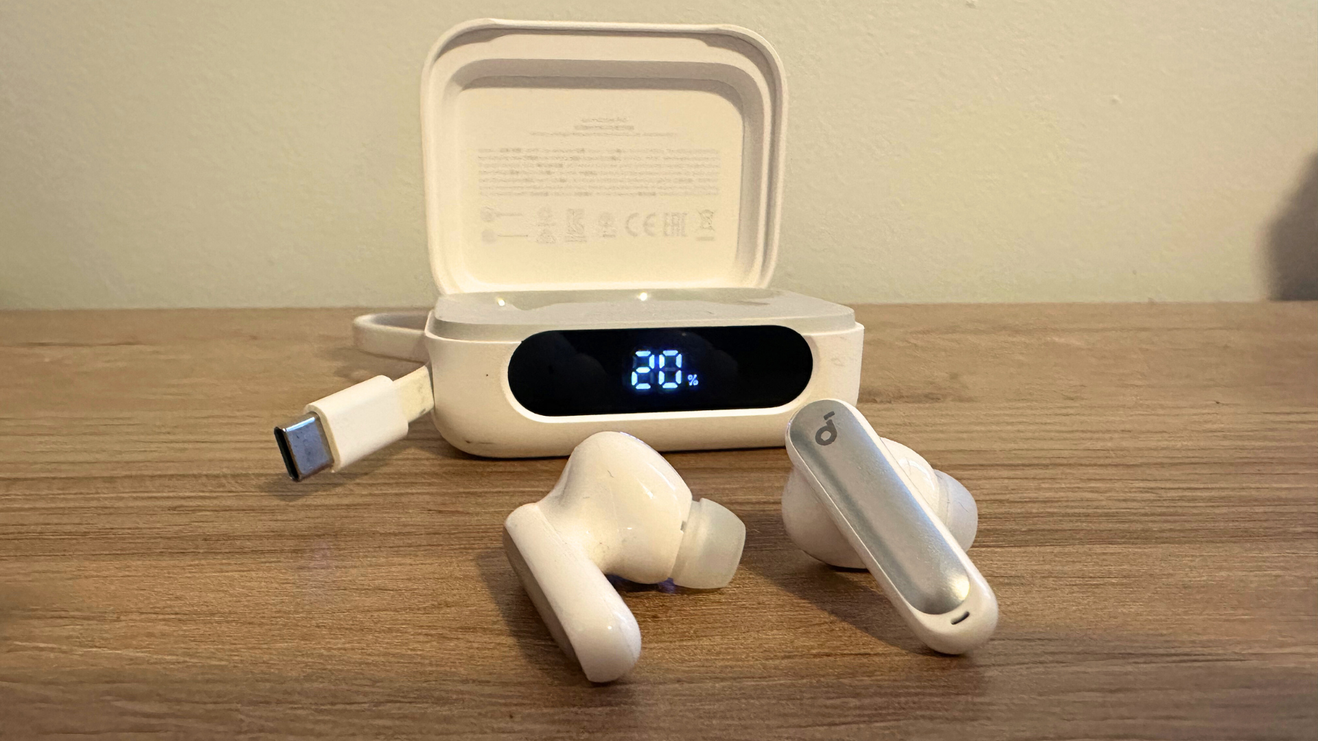 A pair of Soundcore P41i earbuds on a wooden table