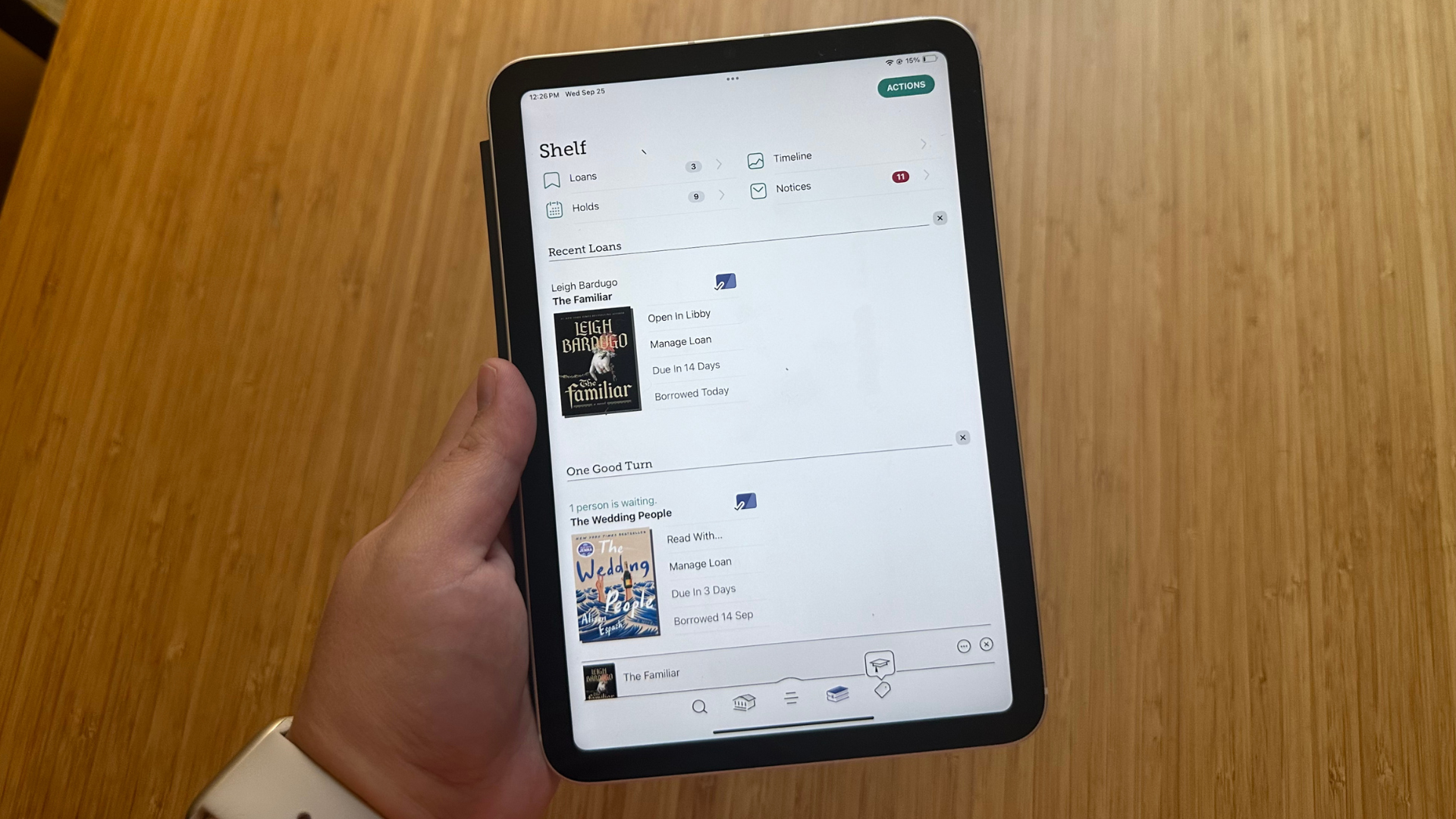 A hand holding an iPad Mini with the Libby app open