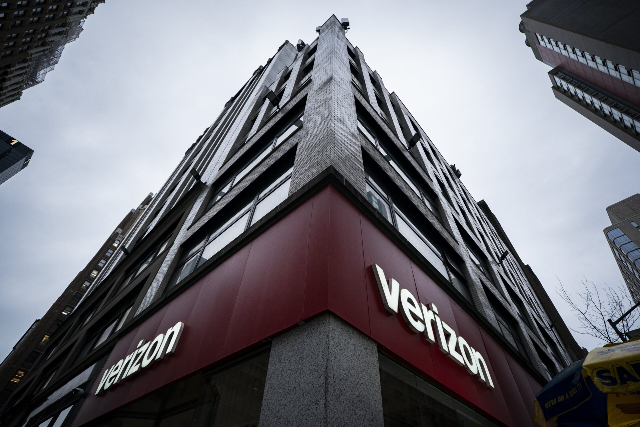 A shot of a tall building from below, with a red Verizon sign on its facade.