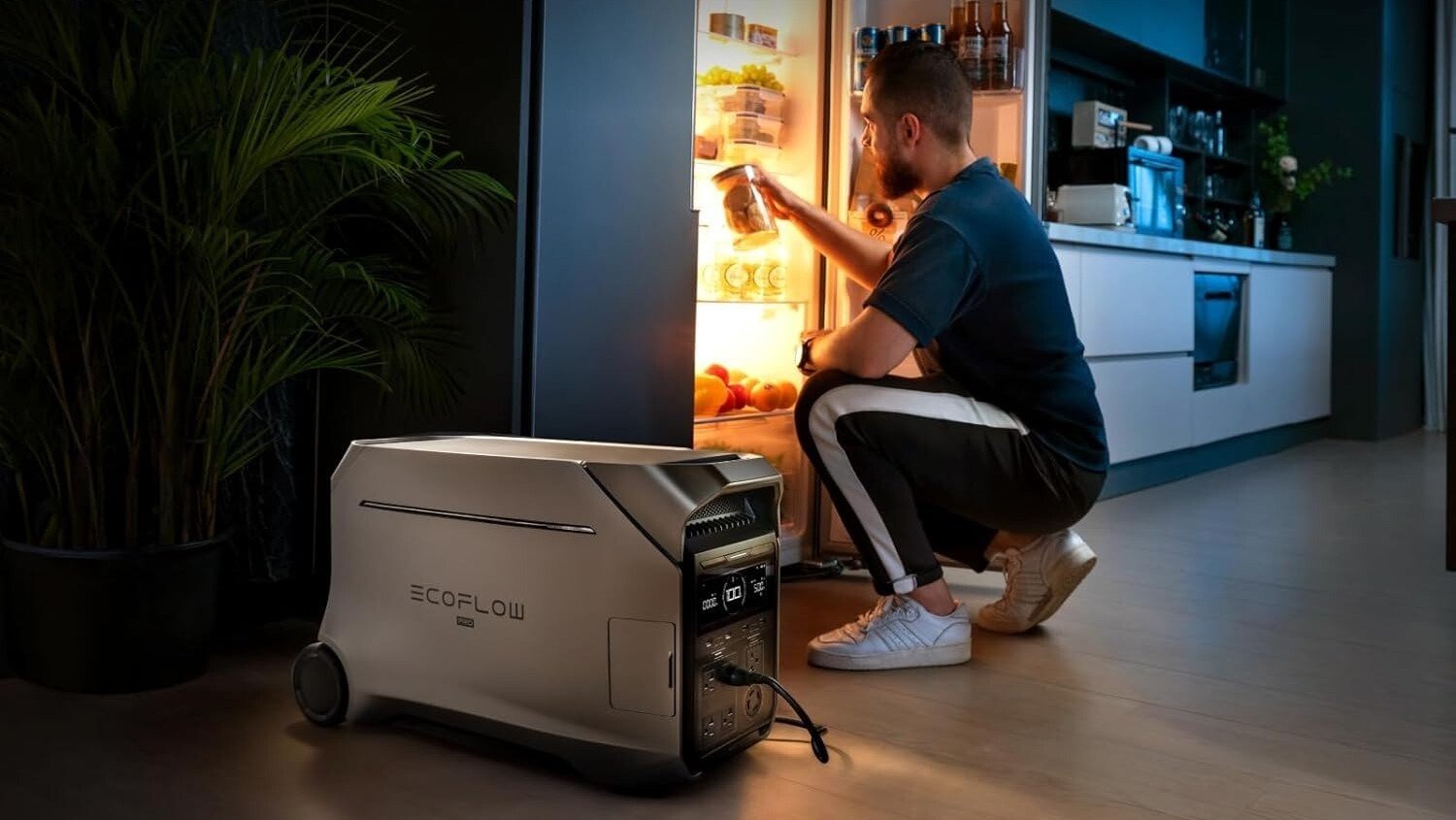 a person is crouched down in front of an open refrigerator which is being powered by the EcoFlow Delta Pro 3