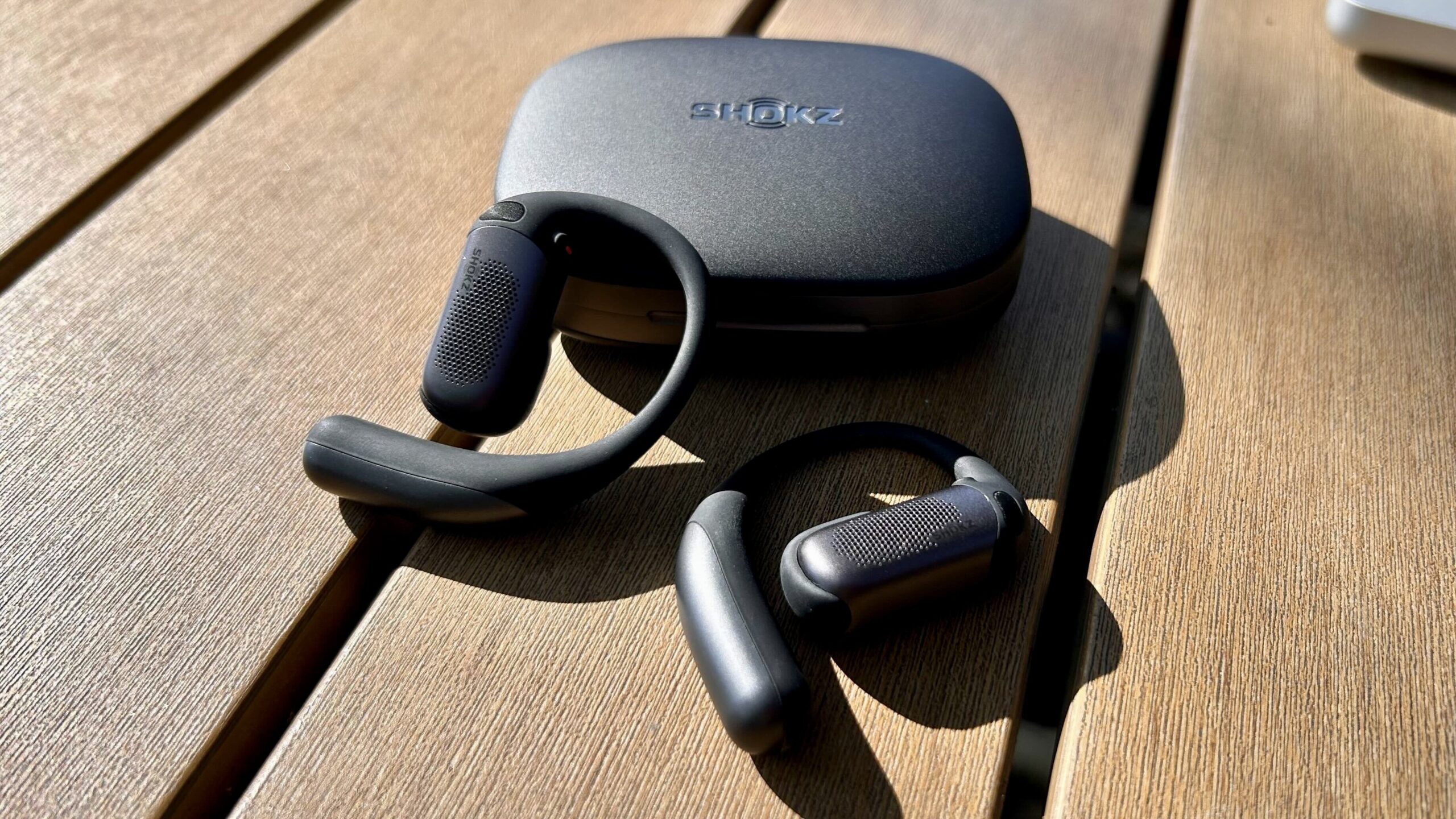 black shokz earbuds on picnic table