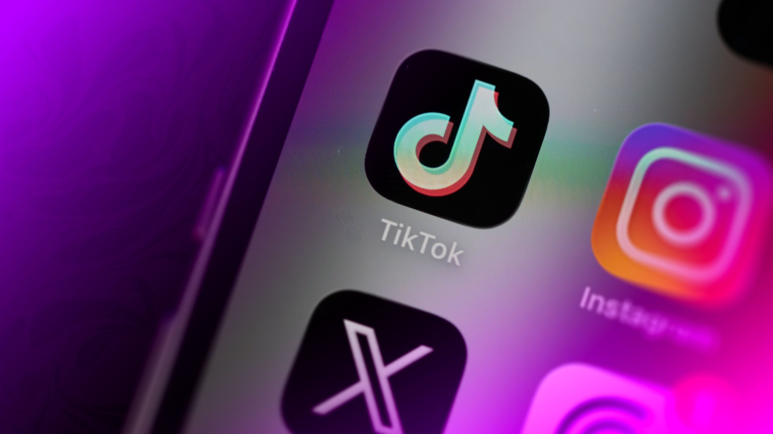 A TikTok icon above an X icon on a smartphone screen.