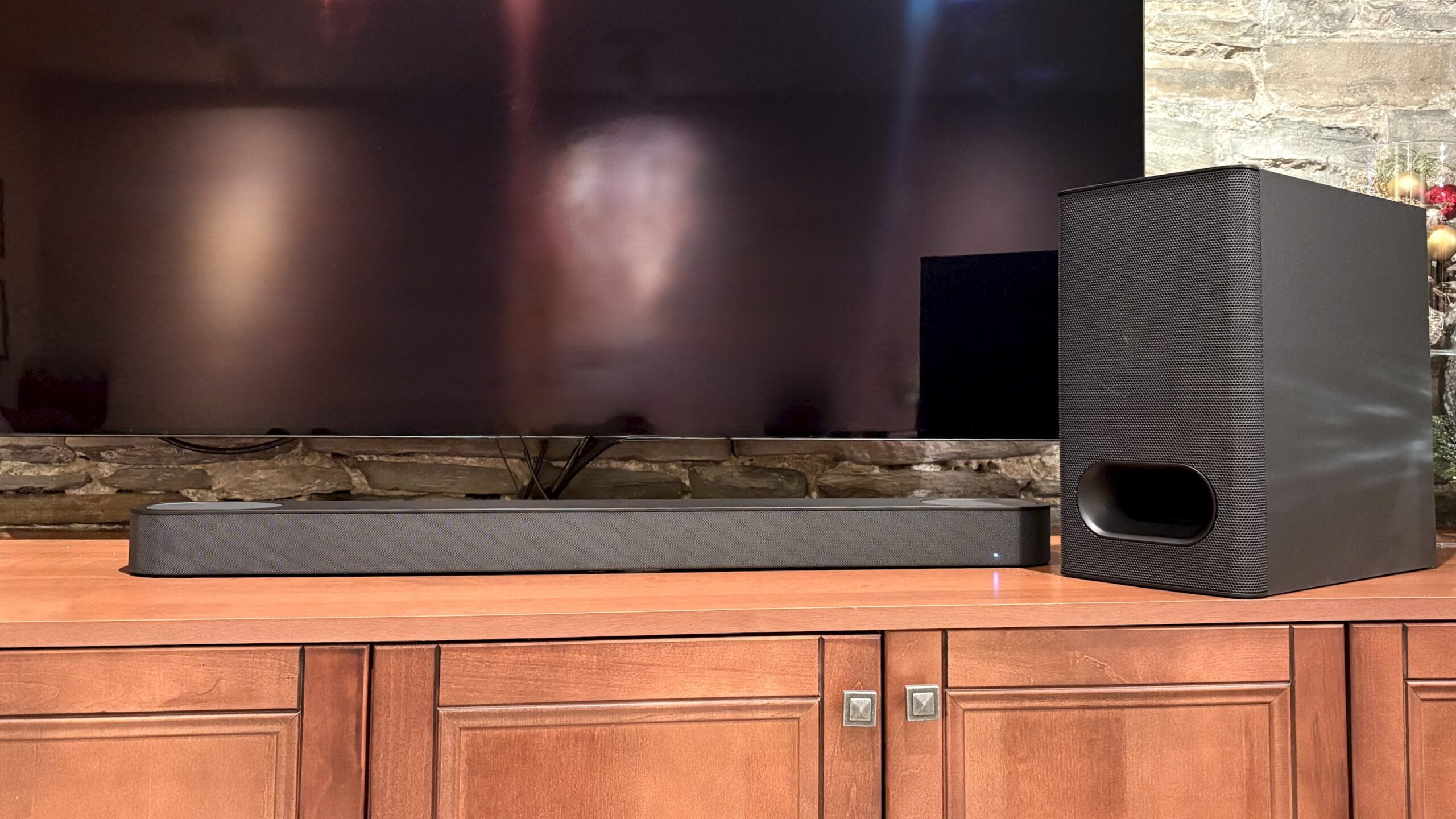 The Sony Bravia Theater Bar 6 speaker and subwoofer sit on a TV console in front of a flat screen tv