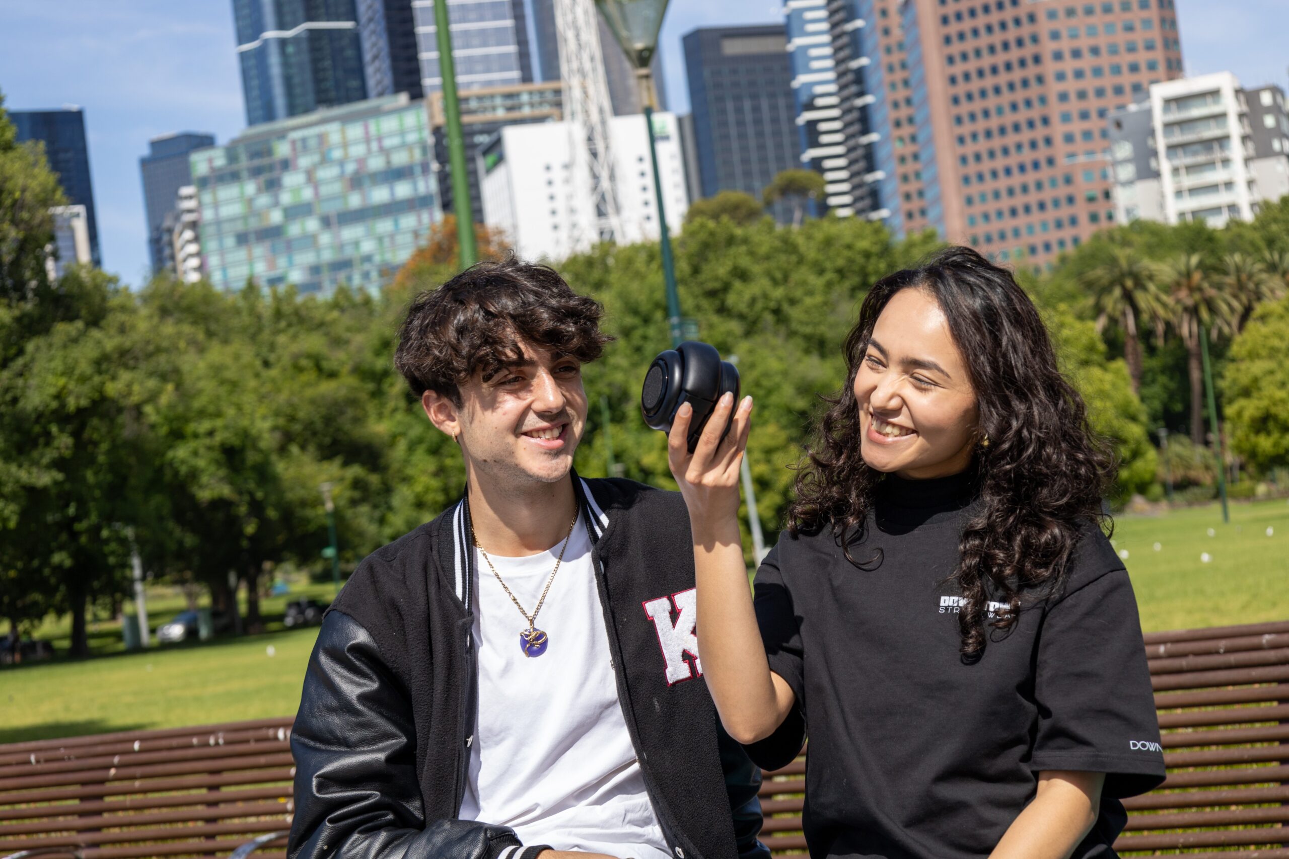 man and woman listening to TDM Neo Hybrid headphones speaker outside