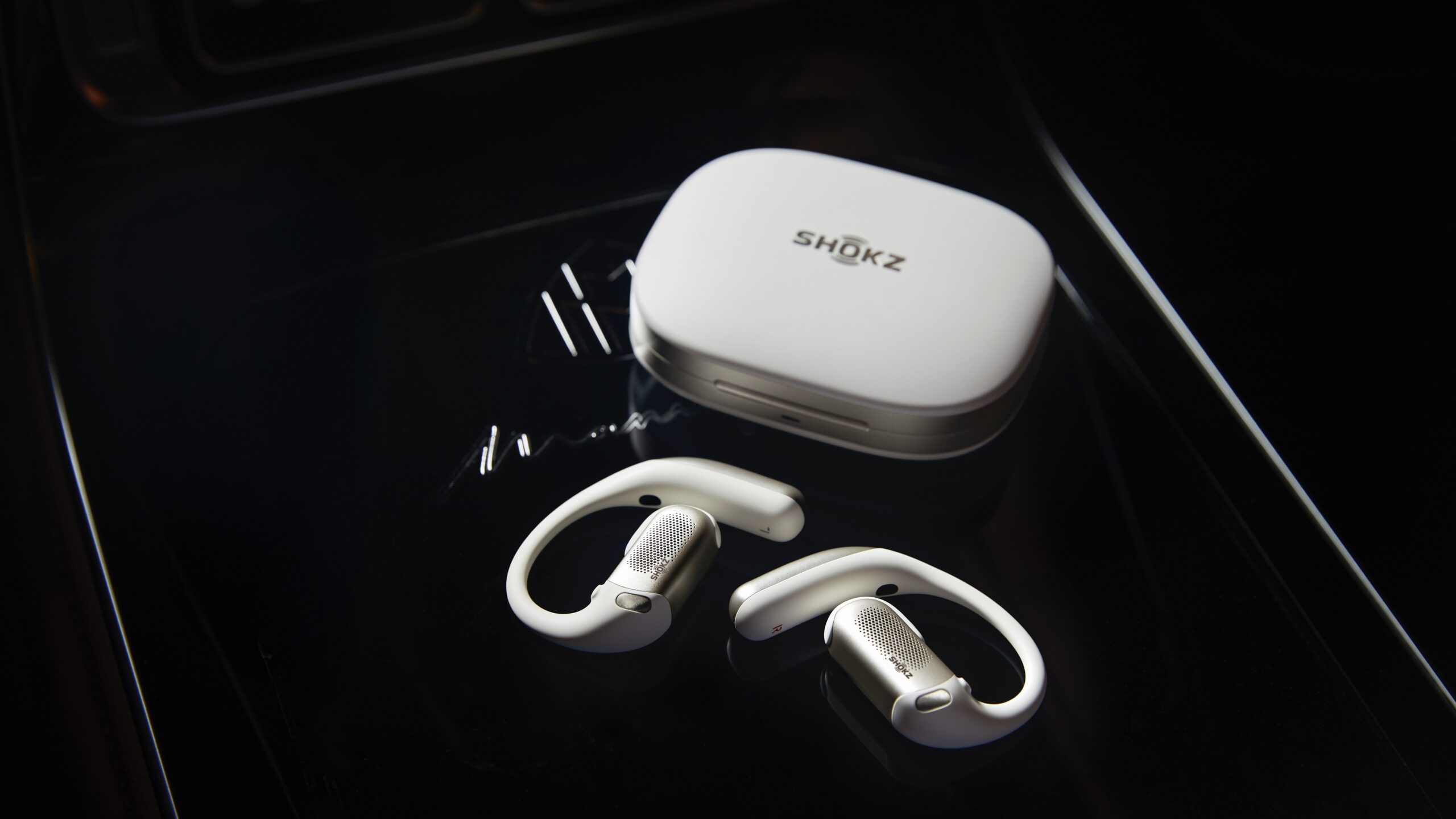 white shokz openfit pro earbuds and case on black table