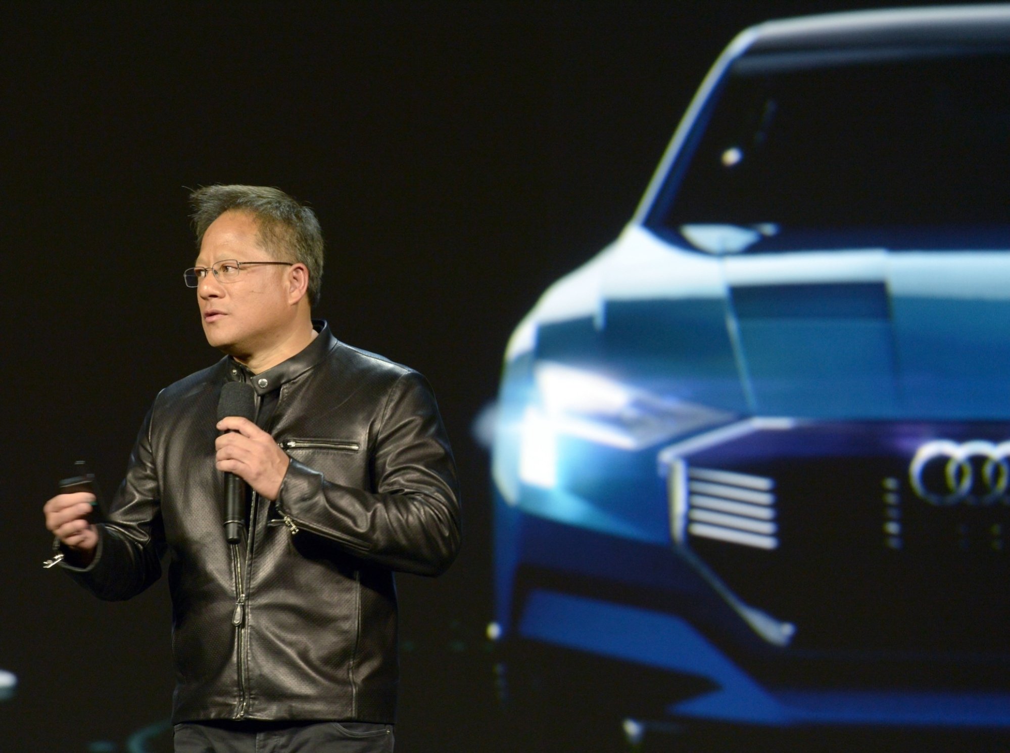 A man in a leather jacket in front of an image of a car