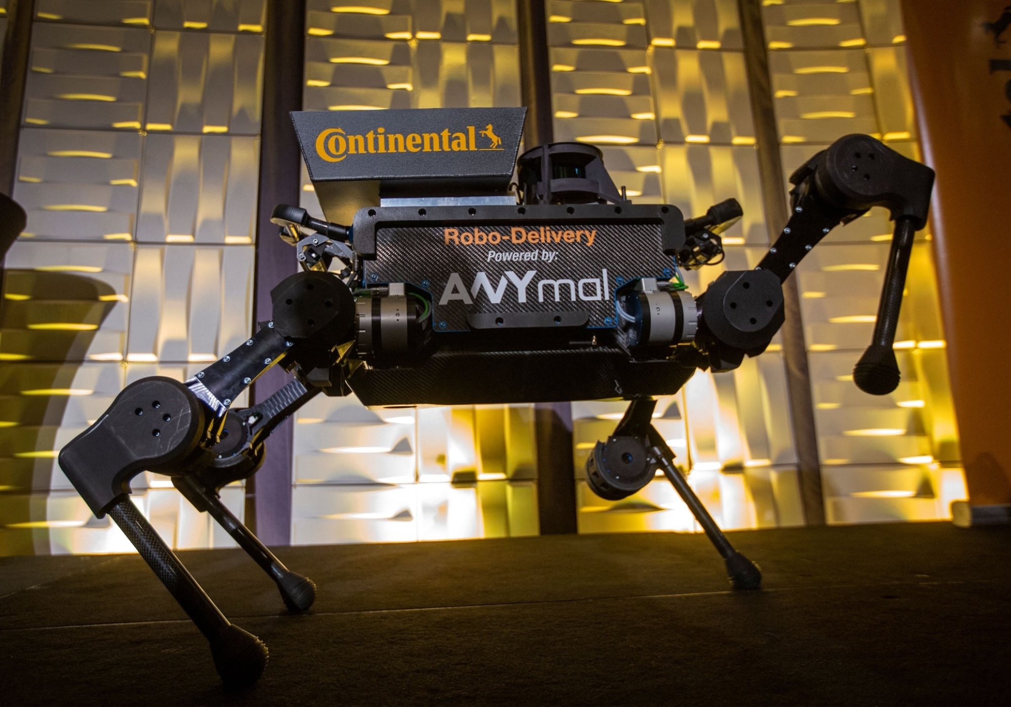 A four legged robot with logos and one leg raised