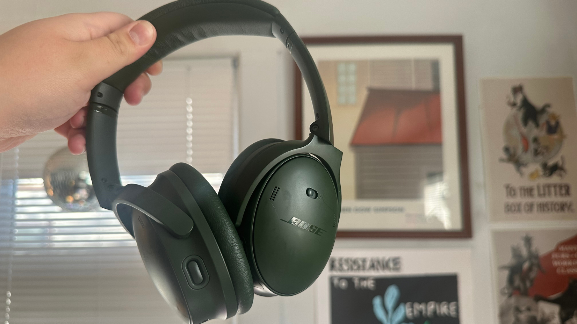 A person holding a pair of Bose QuietComfort headphones