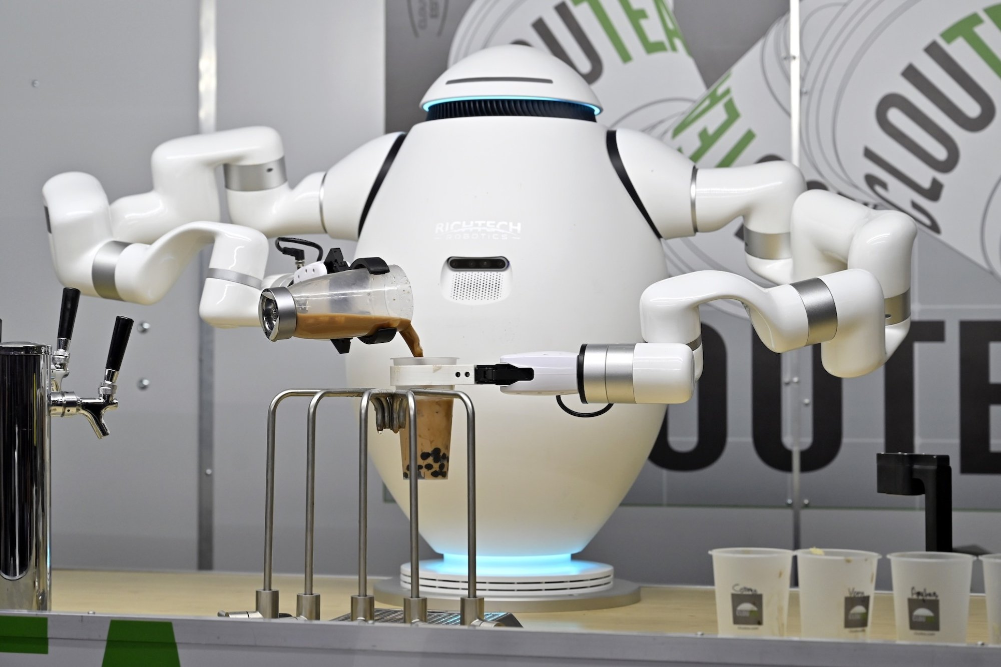 A robot with multiple bendy arms pouring bubble tea