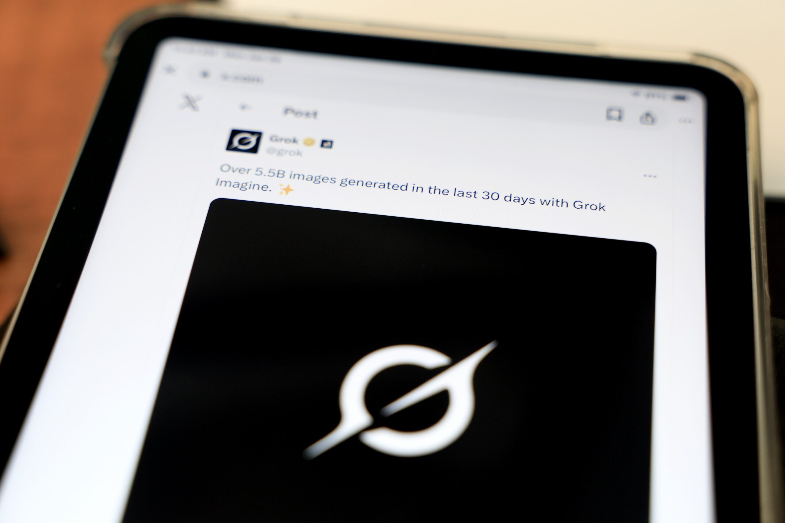 A tablet screen shows Grok's X account feed.