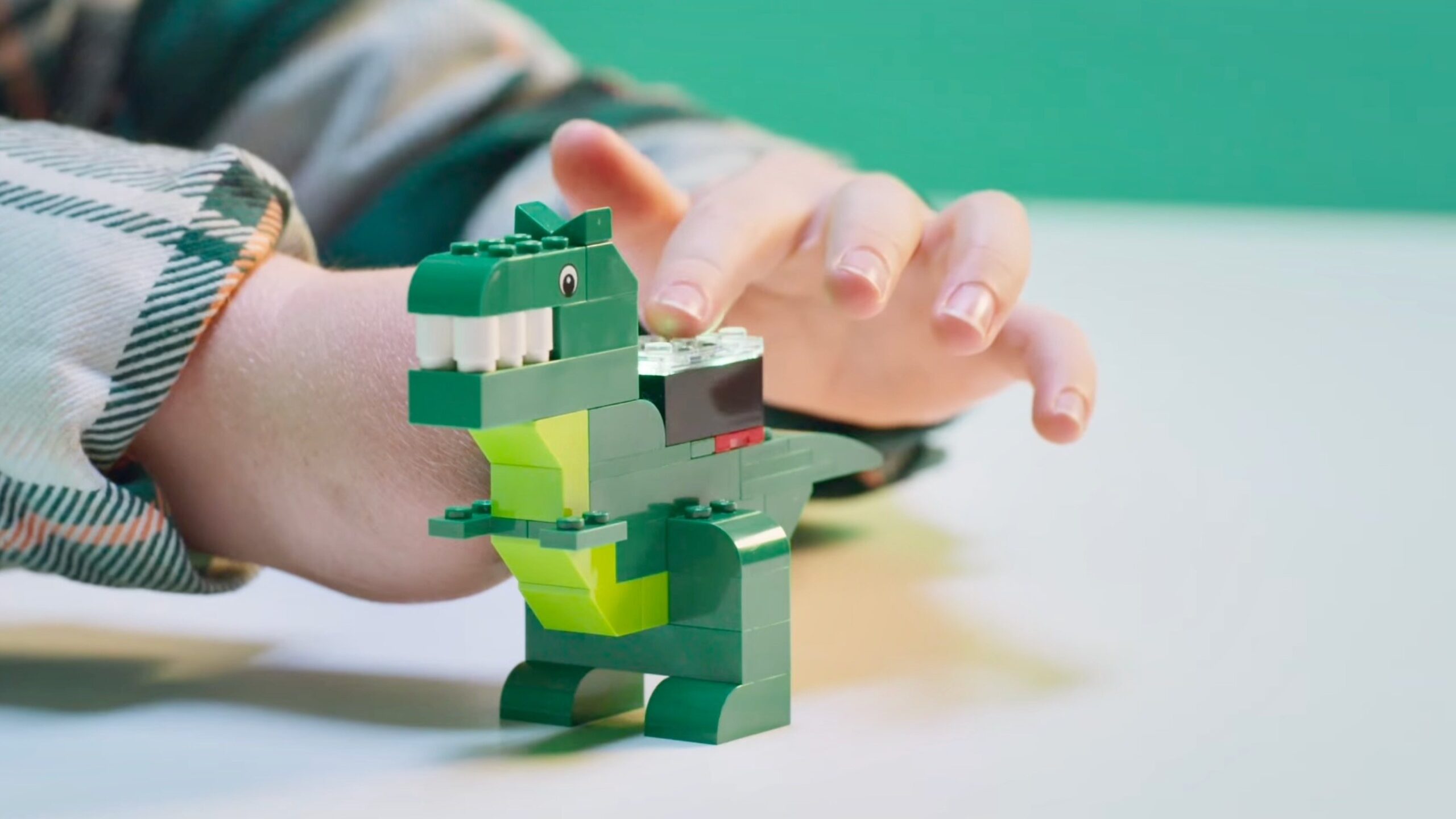child playing with lego smart brick on dinosaur model
