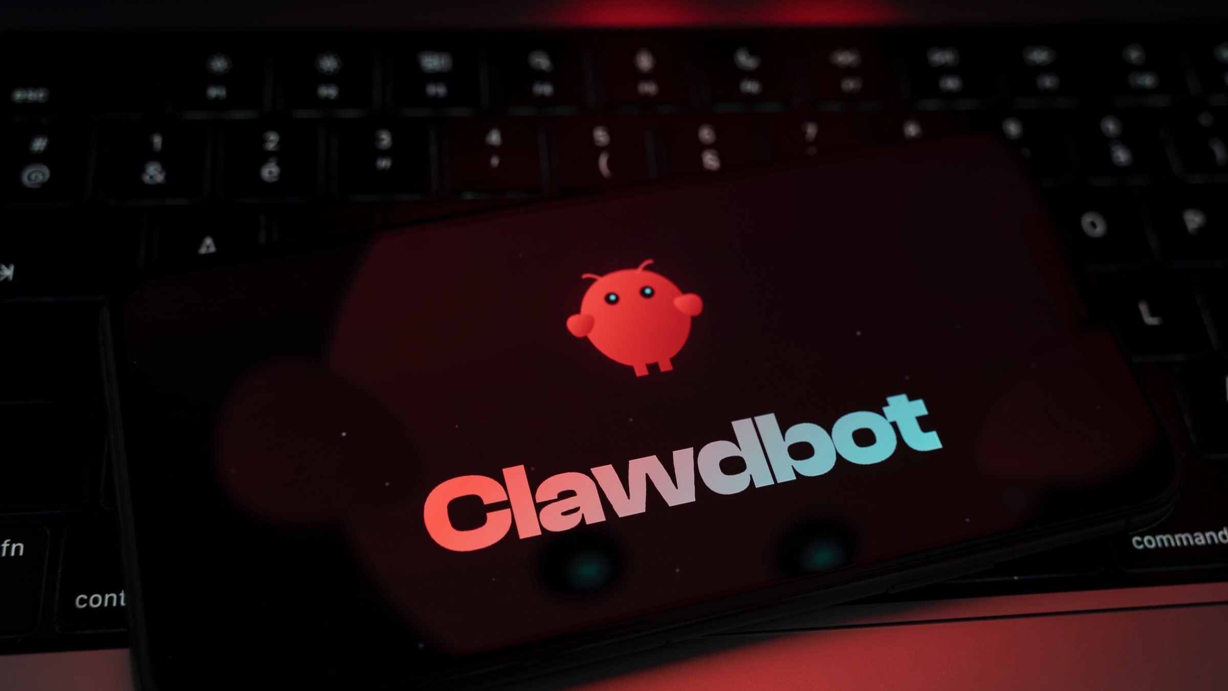 the clawdbot logo and mascot appear on a phone screen in front of a keyboard