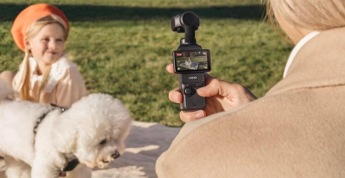 a person operates the DJI Osmo Pocket 3 while filming a white dog and a child