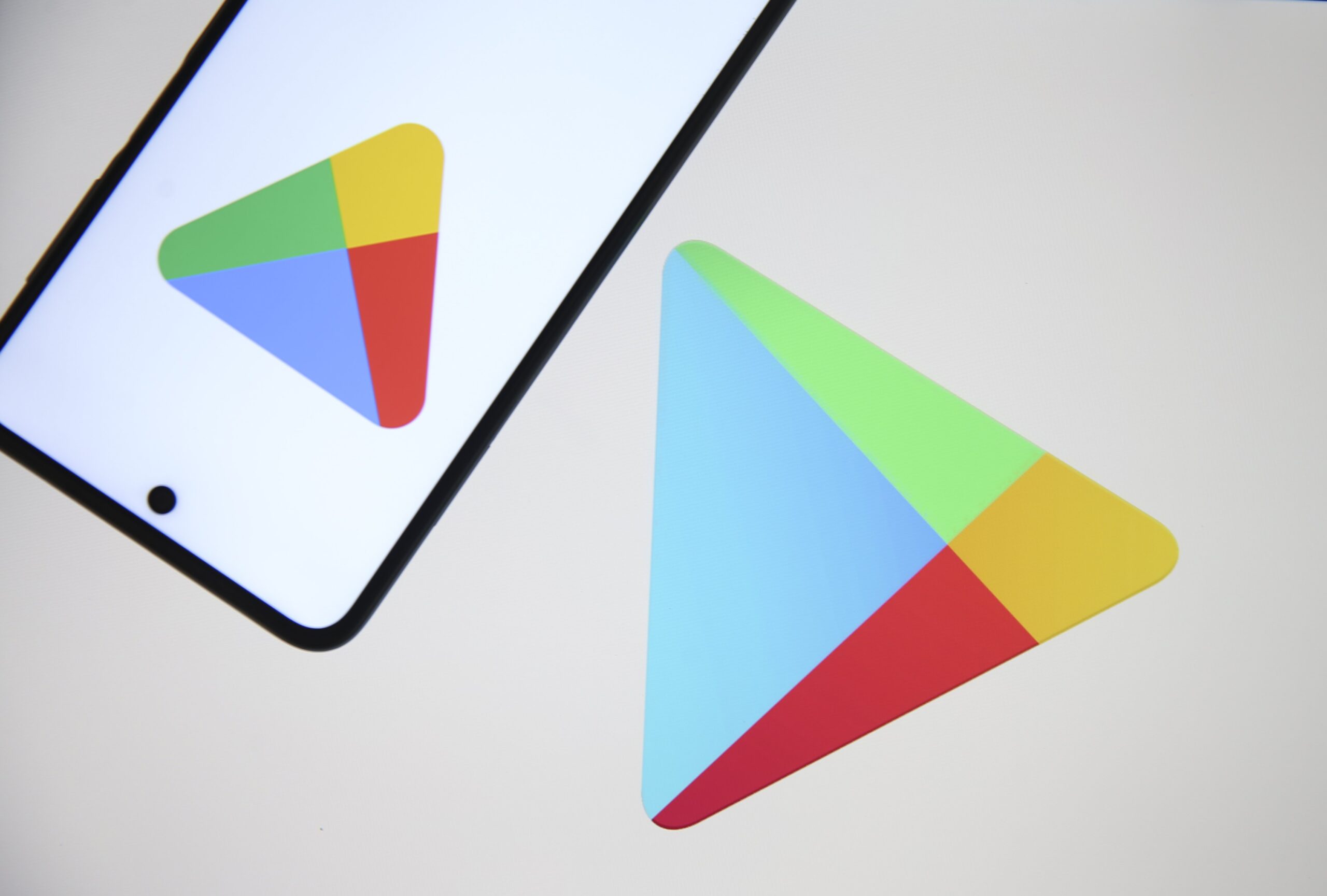 A large Google Play logo on white background next to a phone. 