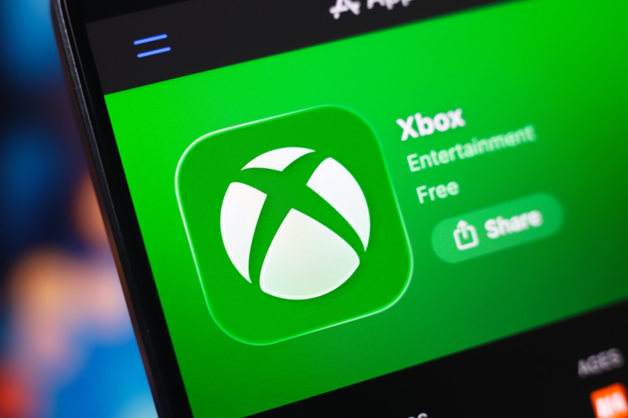 A laptop screen shows the Xbox app homepage.