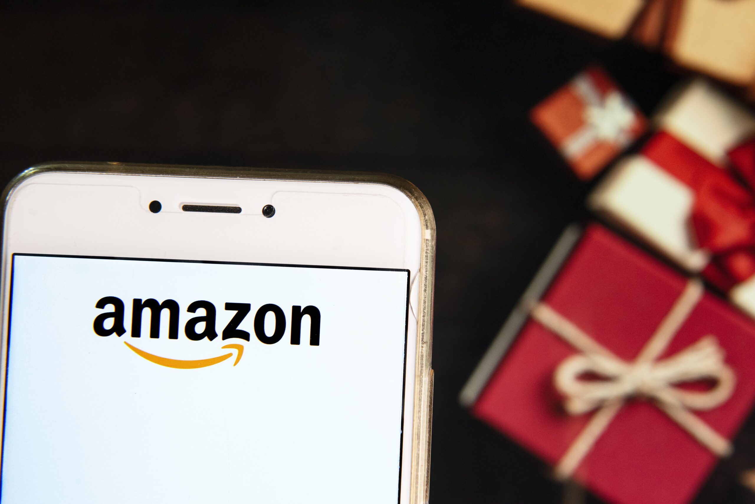 amazon logo on phone in front of gift boxes