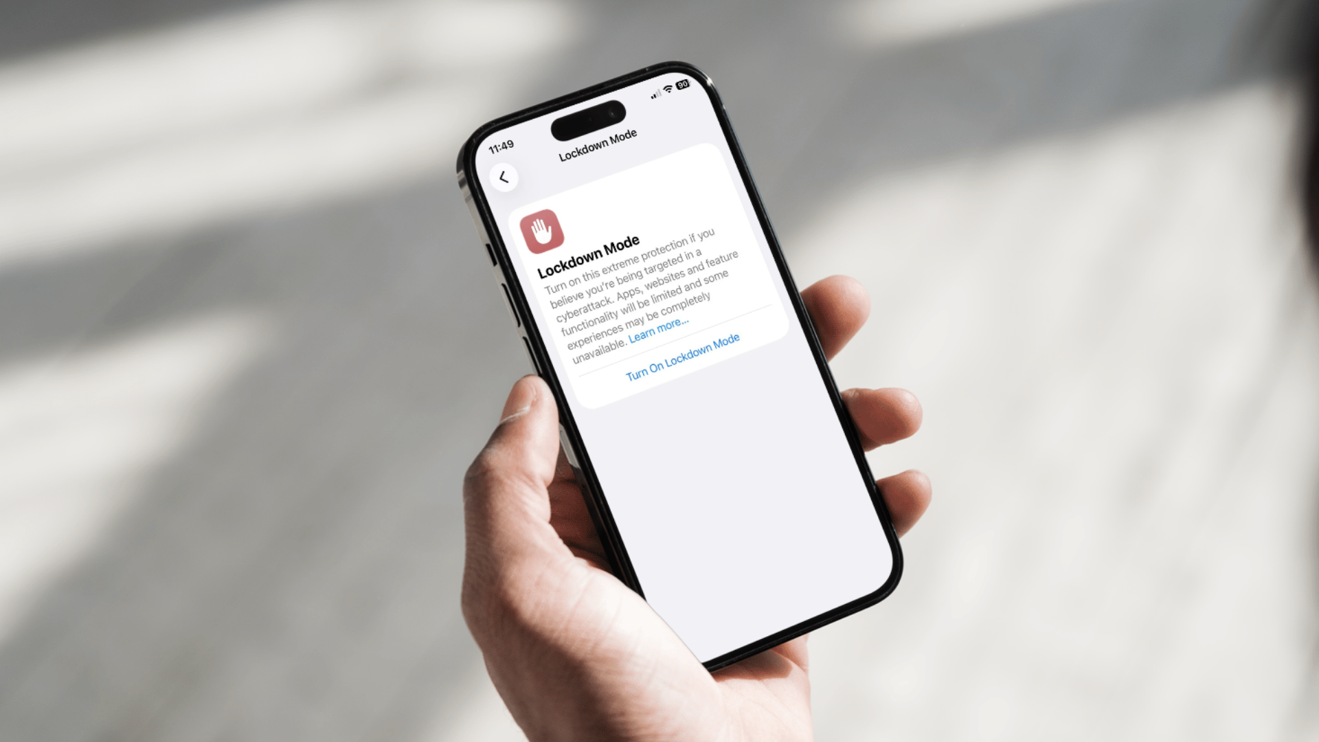 A person holding an iPhone showing the Lockdown Mode screen in settings.