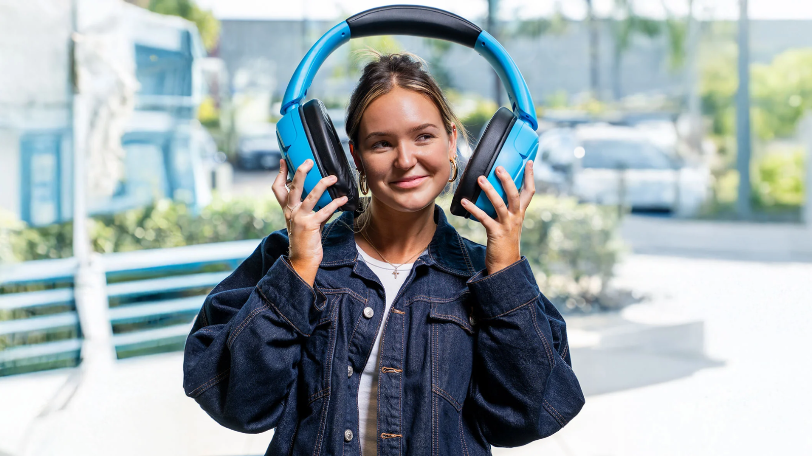 a woman holding a pair of JLab Blue XL Speaker Headphones