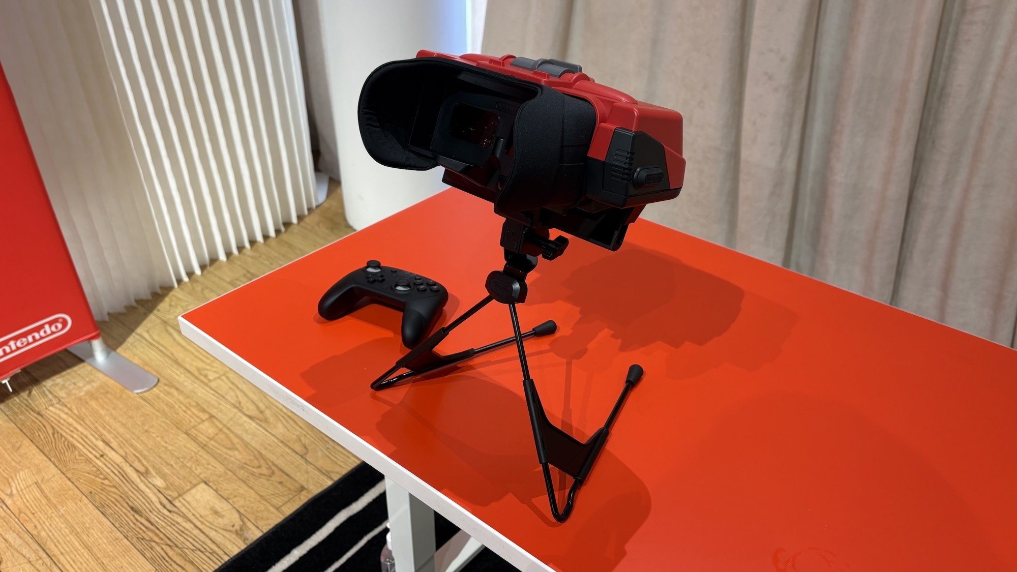 The Switch Virtual Boy add-on viewed from the front, with a Switch 2 Pro Controller sitting next to it