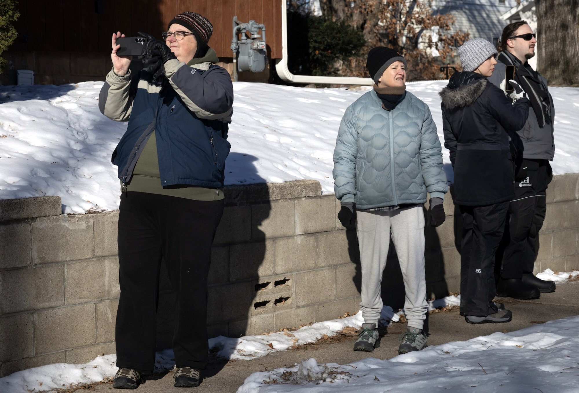 A resident in winter clothes among others, several holding smartphones.