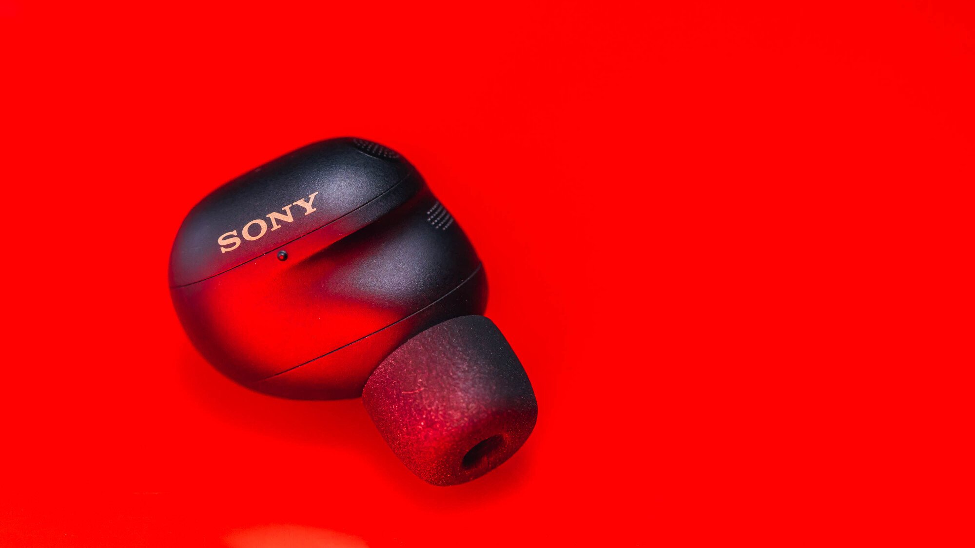 one sony earbud on red background