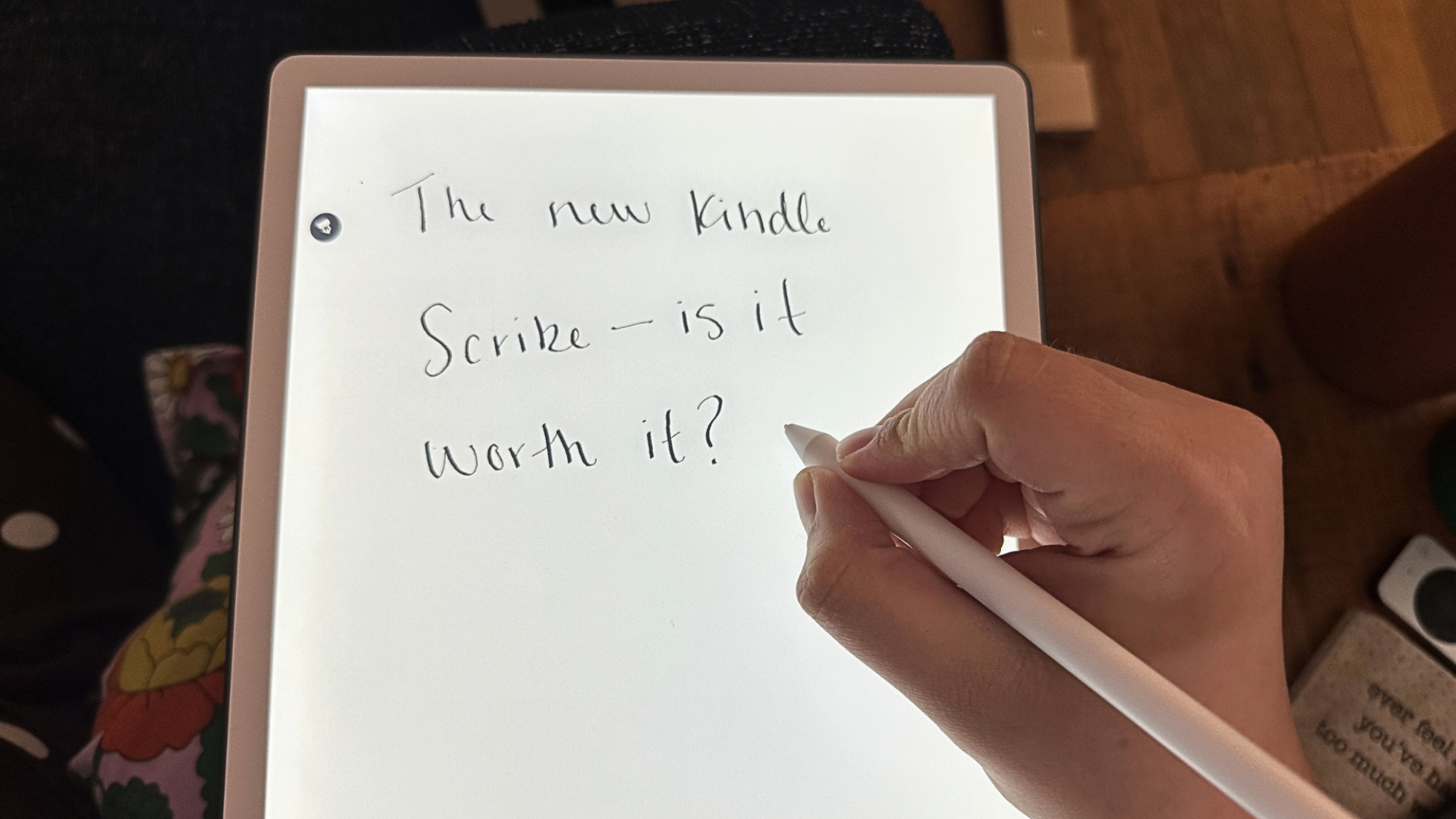 A person writing 'The new Kindle Scribe &mdash; is it worth it?' on a 2025 Kindle Scribe.