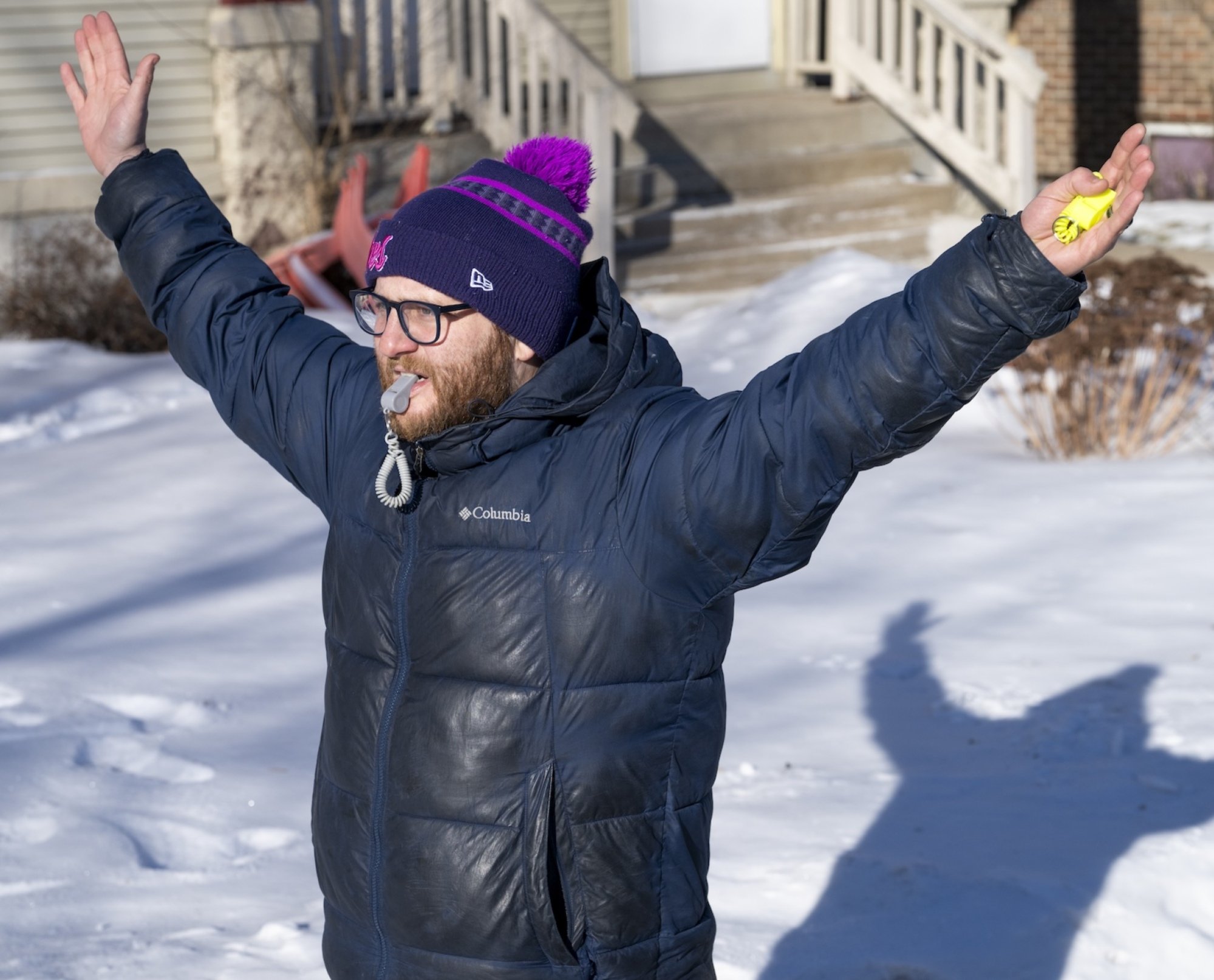 An observer backs away from an ICE agent as he holds a whistle in his mouth
