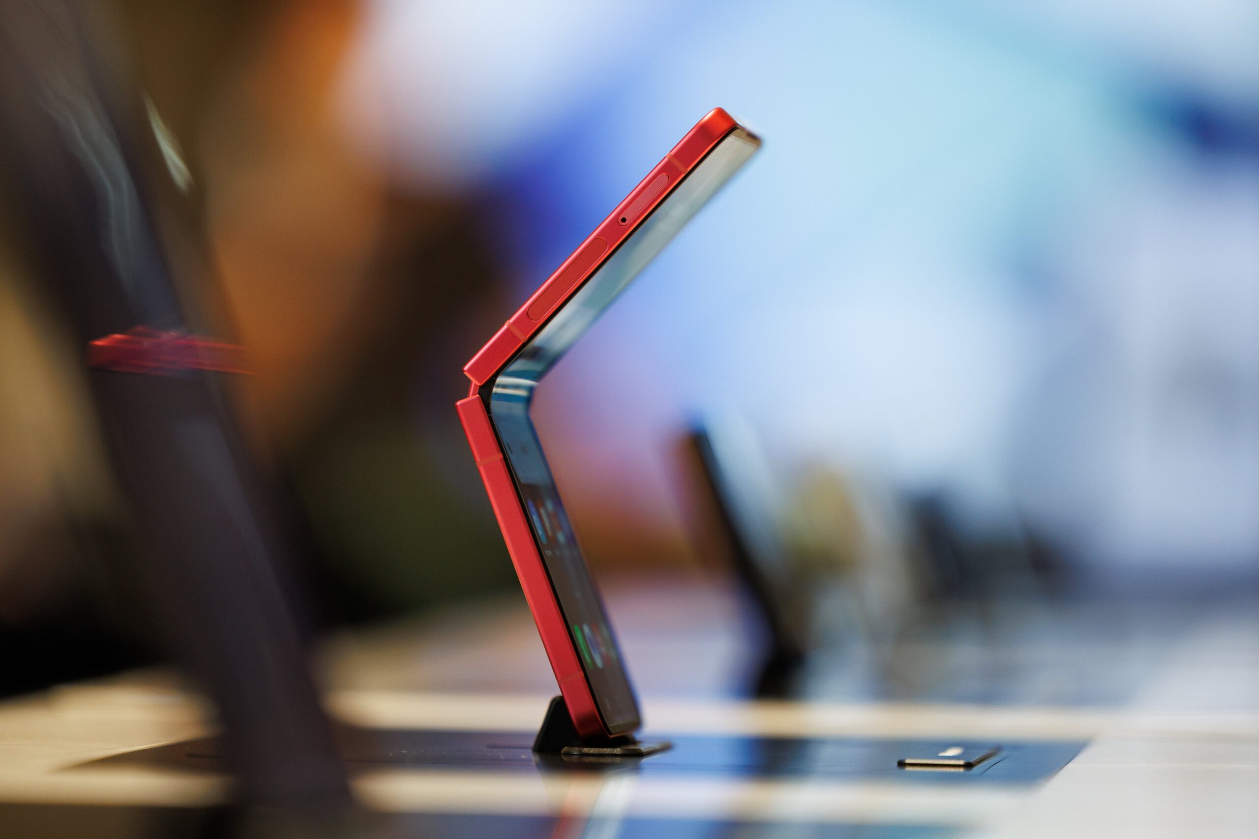 A red Galaxy Z Flip 7 phone on display, it is partially folded in half. 