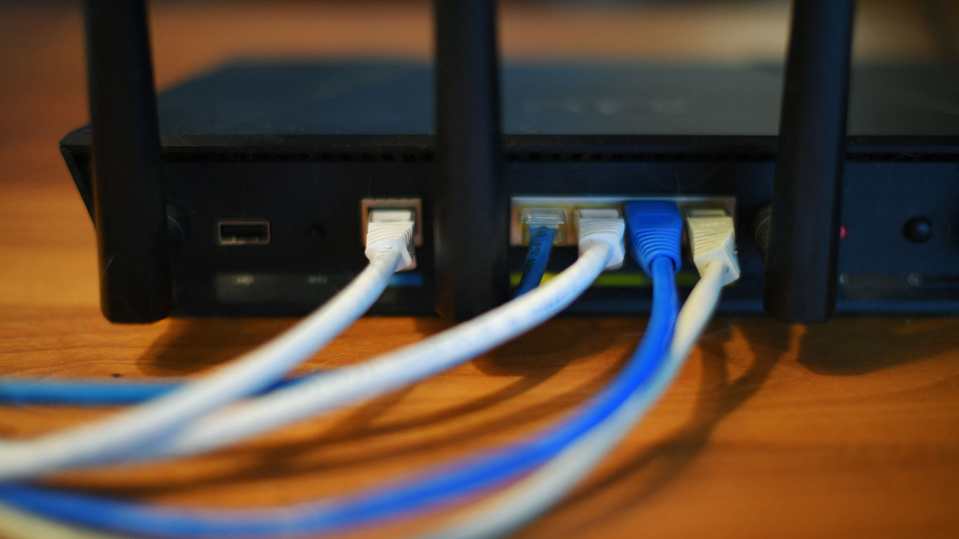 Ethernet cables are seen running from the back of a wireless router.