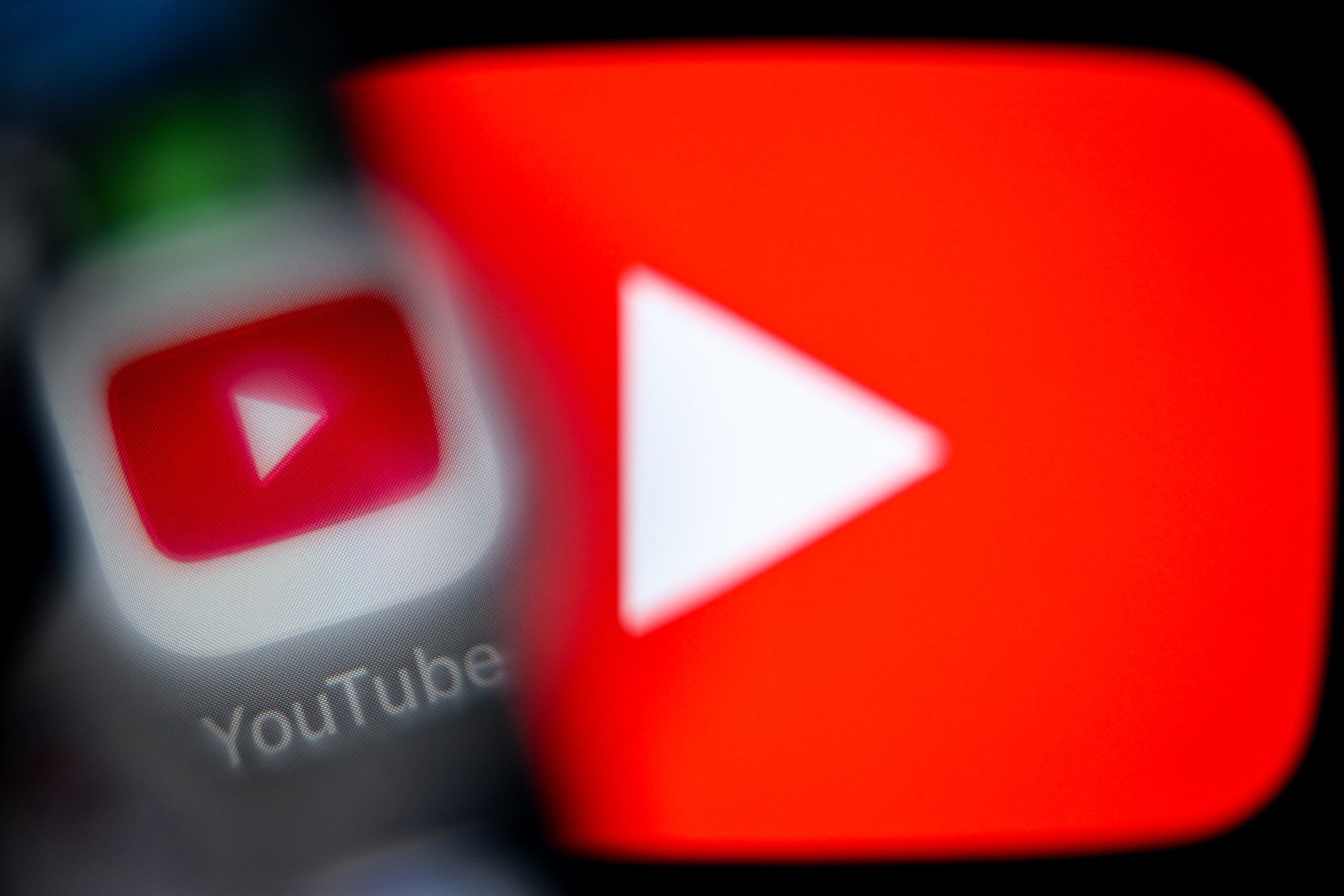 A blurry YouTube app icon over a large glowing YouTube play logo.