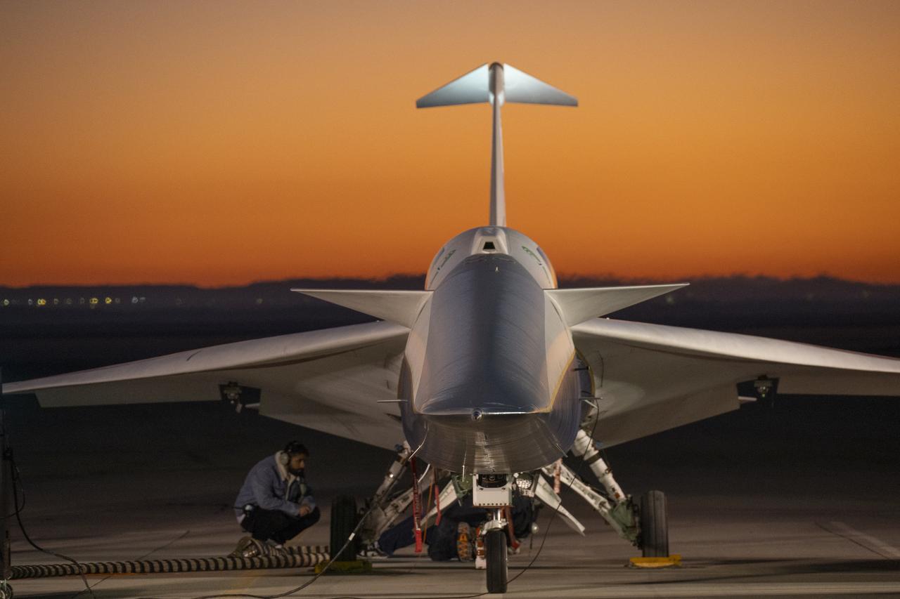 A technician inspecting the X-59 plane near its landing gear as the engine runs