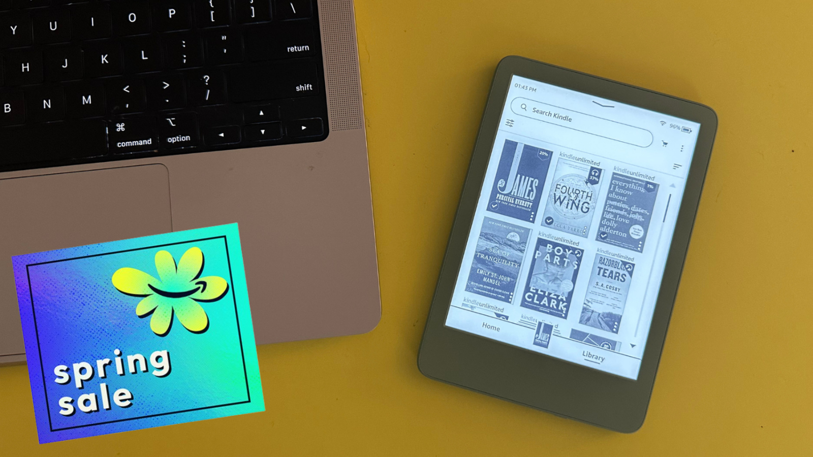 Kindle next to laptop with yellow background and Spring Sale sticker overlay