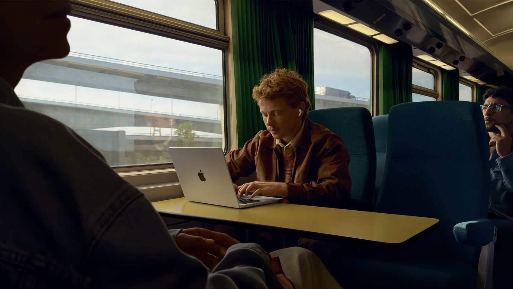 person working on laptop on train wearing apple airpods pro 3