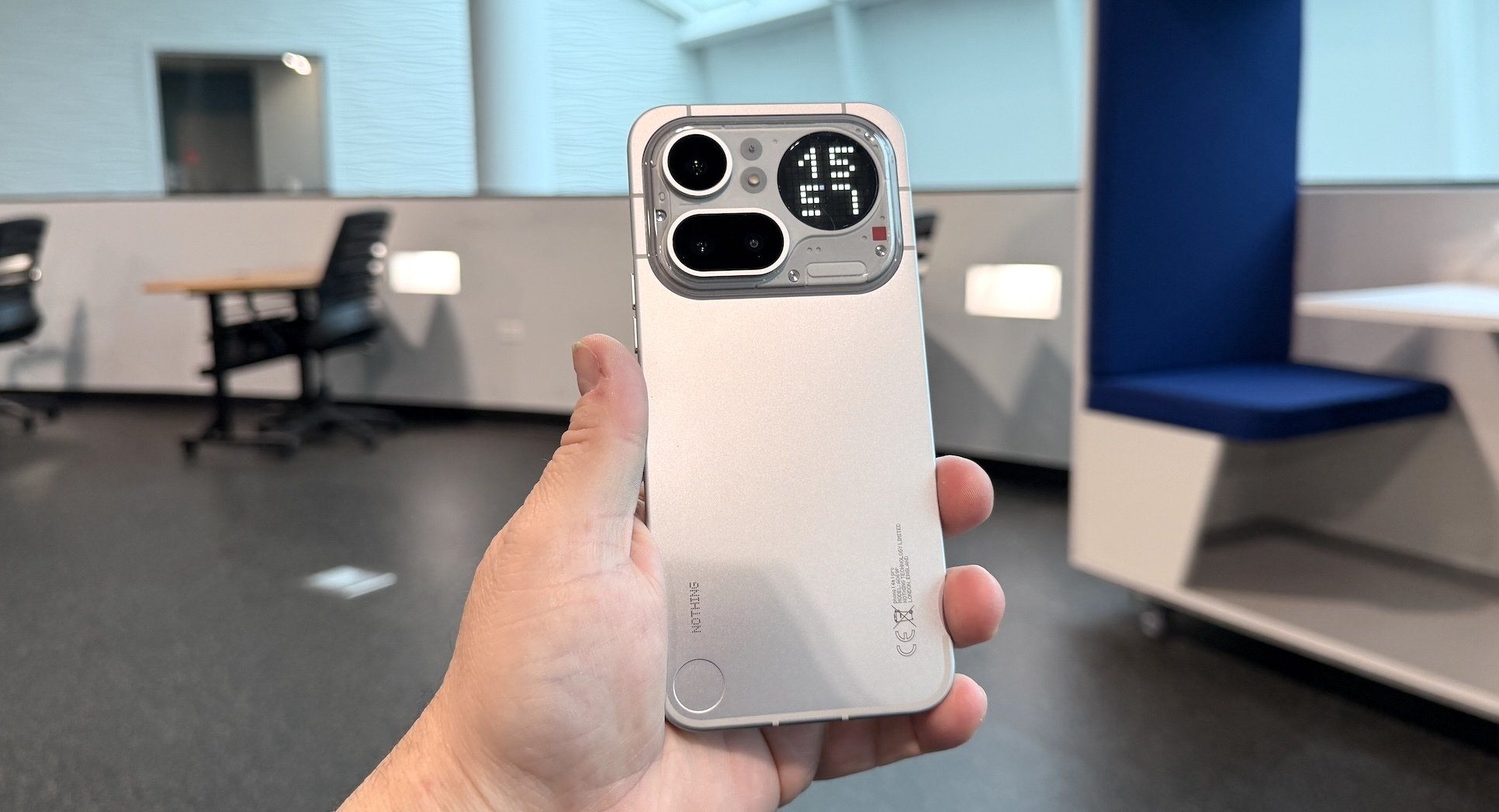 The Nothing phone with rear cameras and digital display held in a hand