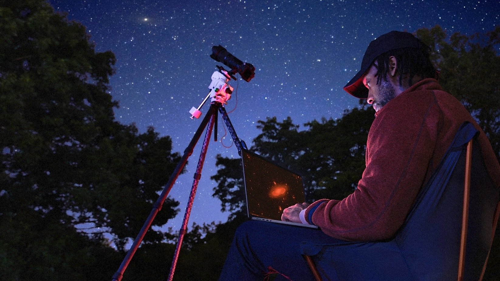 man using m5 macbook pro with telescope at night for astrophotography