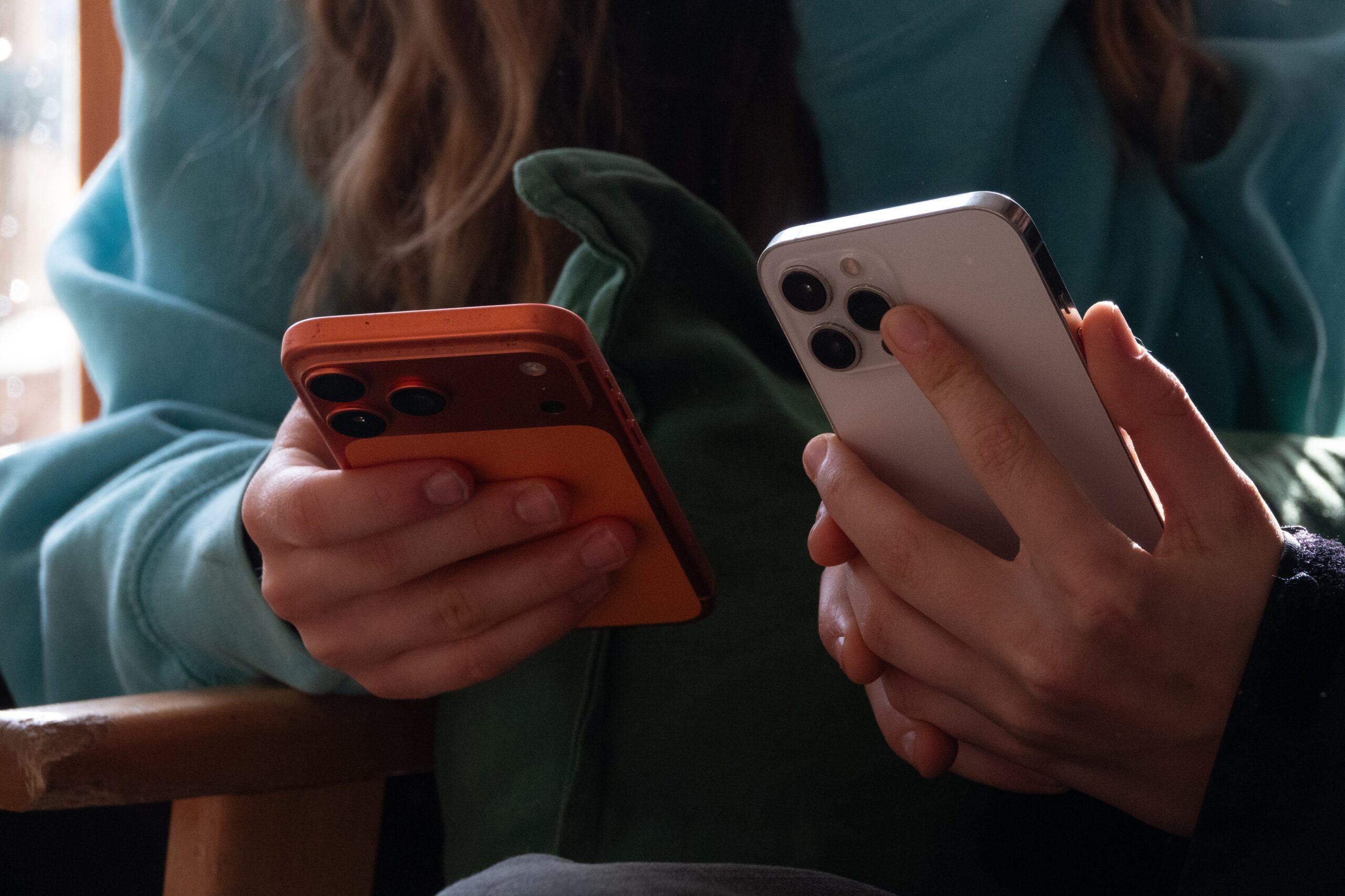 In this photo illustration two teenagers aged 14-years-old look at their iPhone screens displaying various social media and messaging apps
