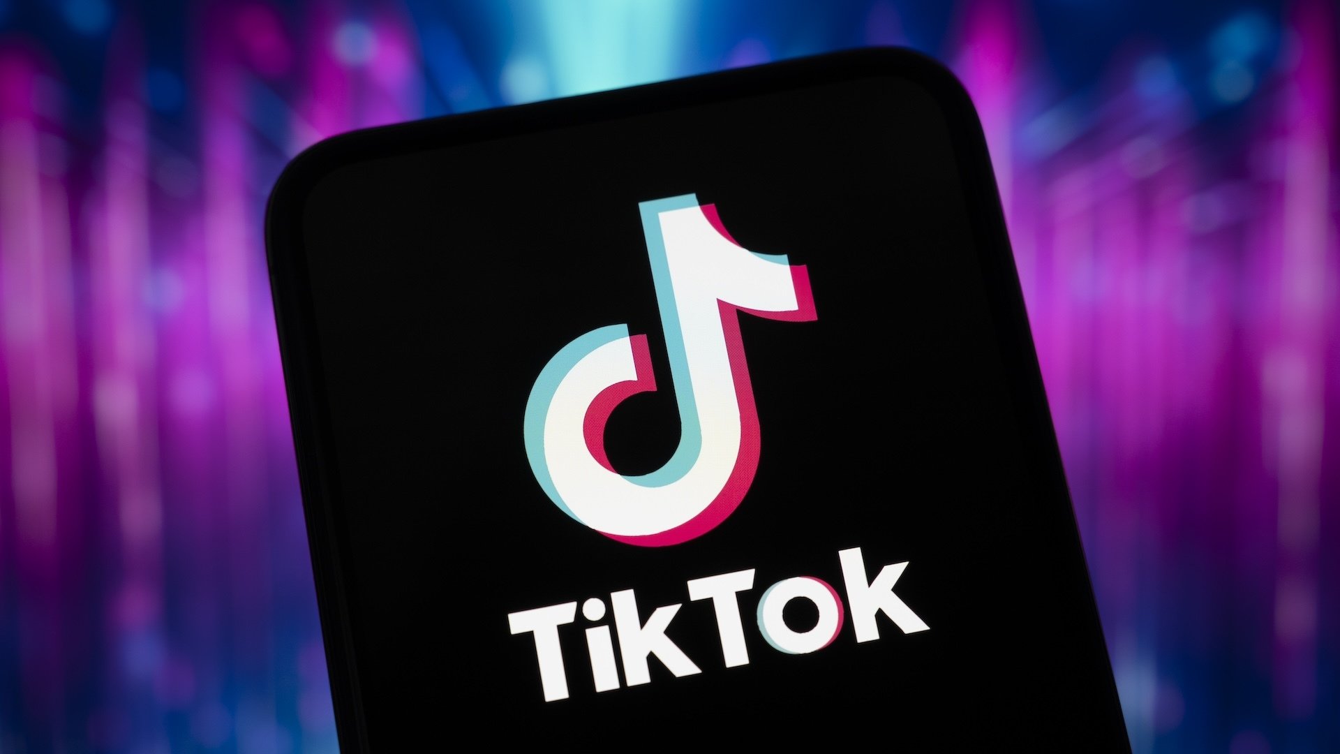 TikTok logo on a smartphone on top of a colorful background.